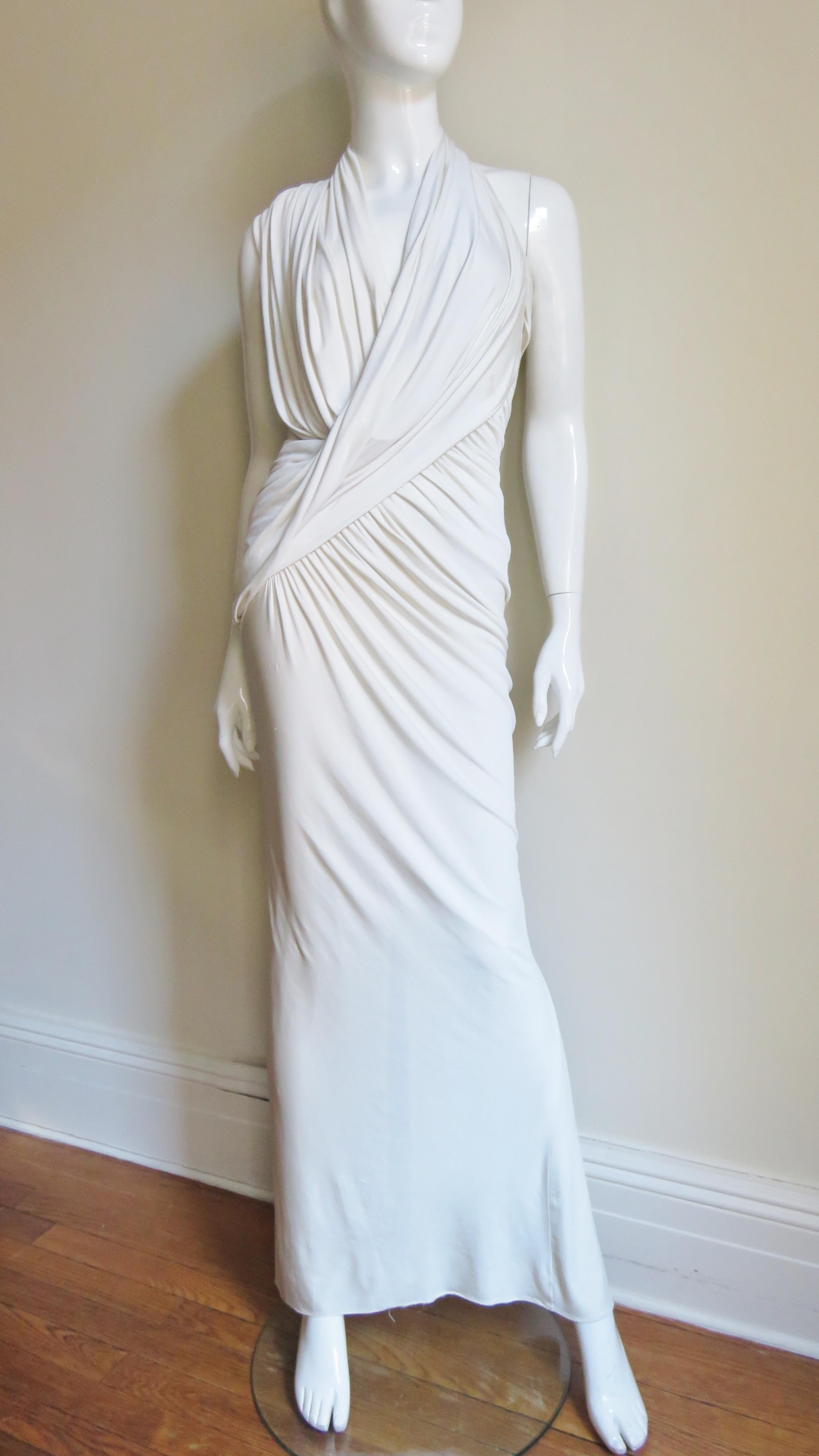 A beautiful white silk jersey dress gown from Donna Karan.  It has a plunging, crossing ruched halter neckline.  There is angled ruching across front skirt, the derriere, and draping at the upper back.  The back skirt has added fullness below the