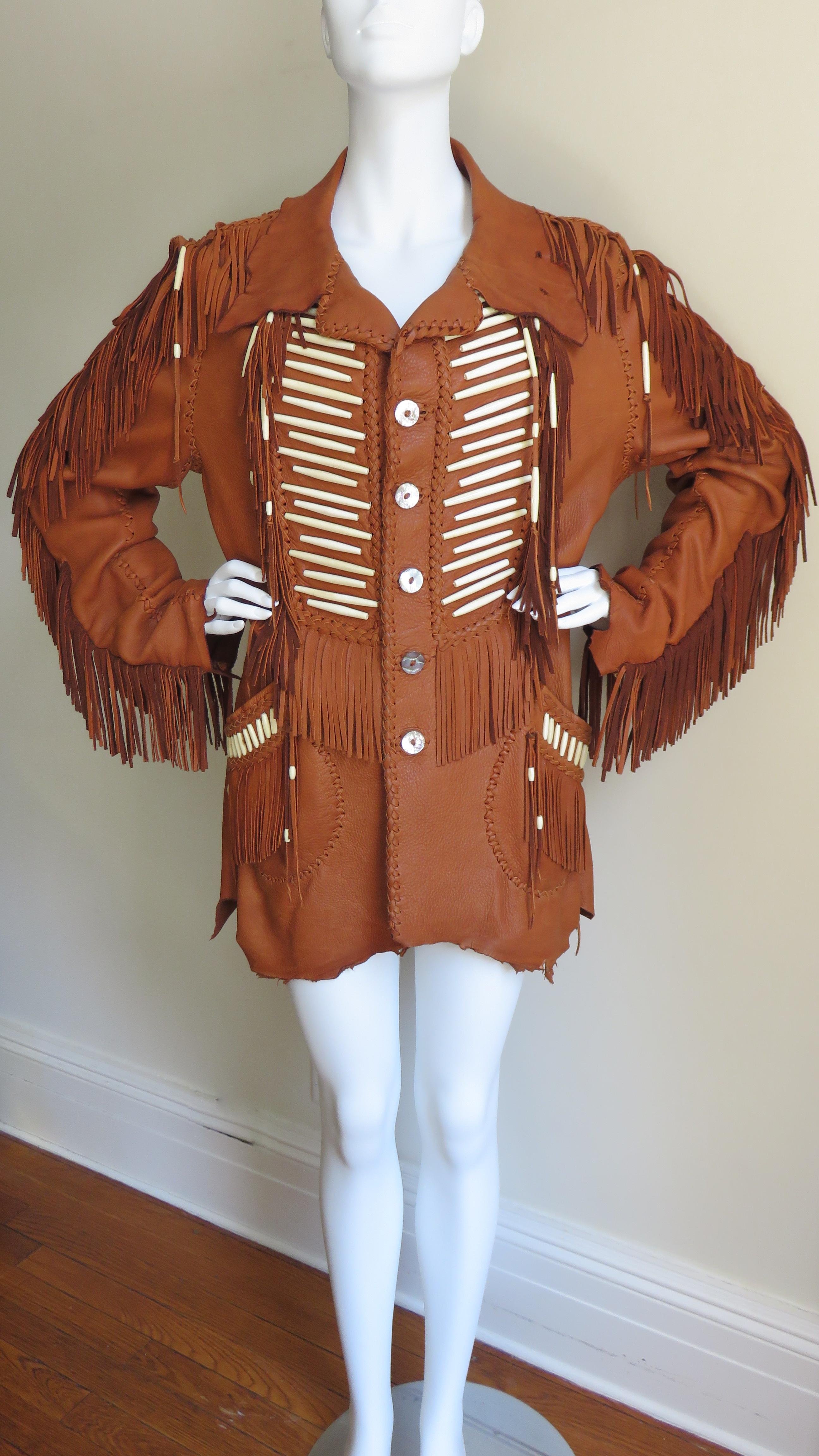 An absolutely amazing tan fringe leather jacket with carved bone detail.  The collar, cuffs and hem follow the natural lines of the hide, the other edges and seaming are highlighted with intricate hand braiding and knotting.  The outside of the