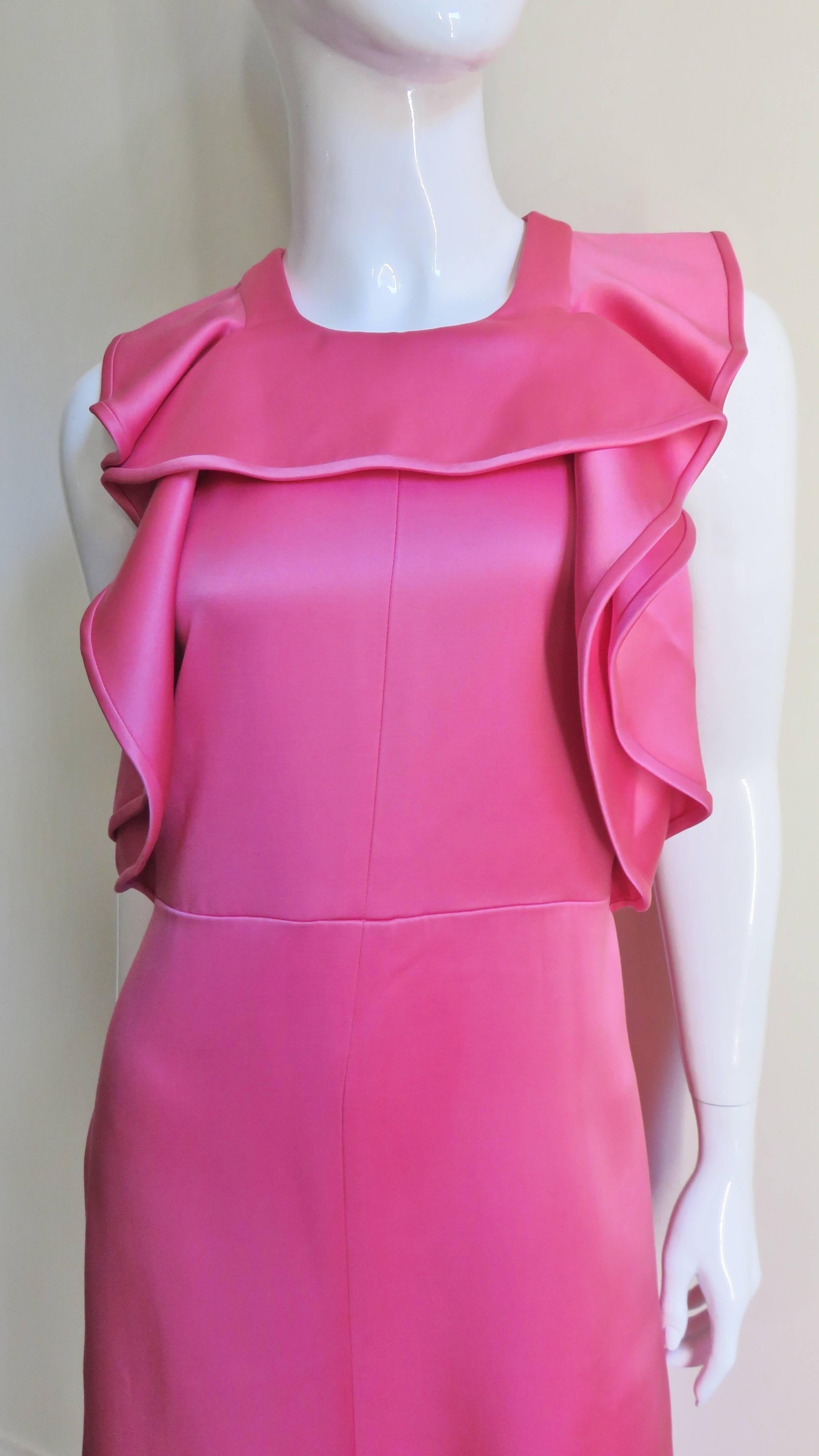 A gorgeous rose silk satin gown from Chloe. It has a 2 ruffles on the front bodice, one that comes from the side seams over the shoulders and the other which crosses at the neckline.  There are inset cap sleeves and a seam at the waist with a long