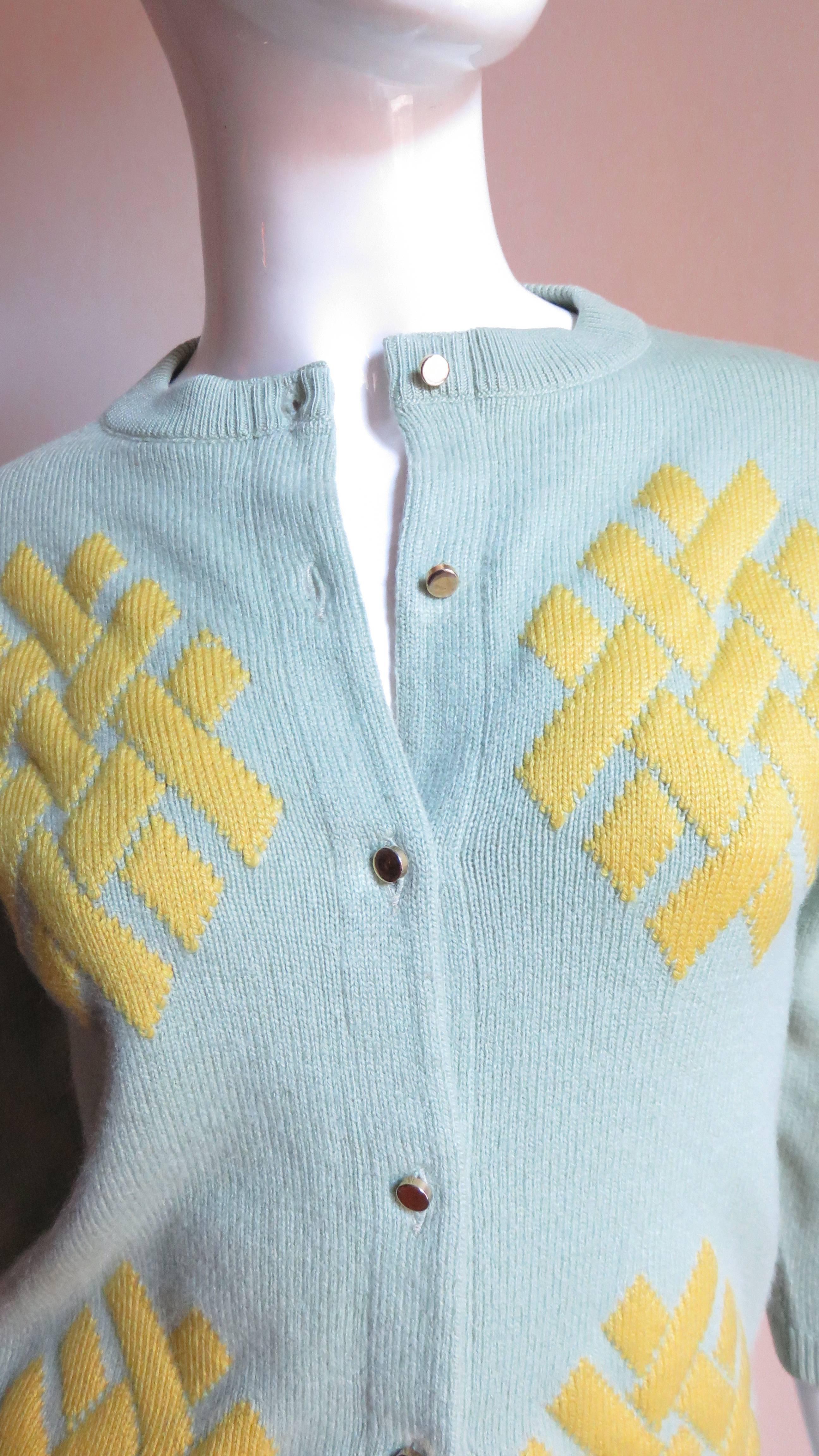 A pretty light green and yellow soft cashmere sweater from Bonnie Cashin.  It has 3/4 length sleeves and closes up the front with small gold metal buttons.  The crew neck, cuffs and hem are all ribbed.  There are 4 patches of yellow in a geometric