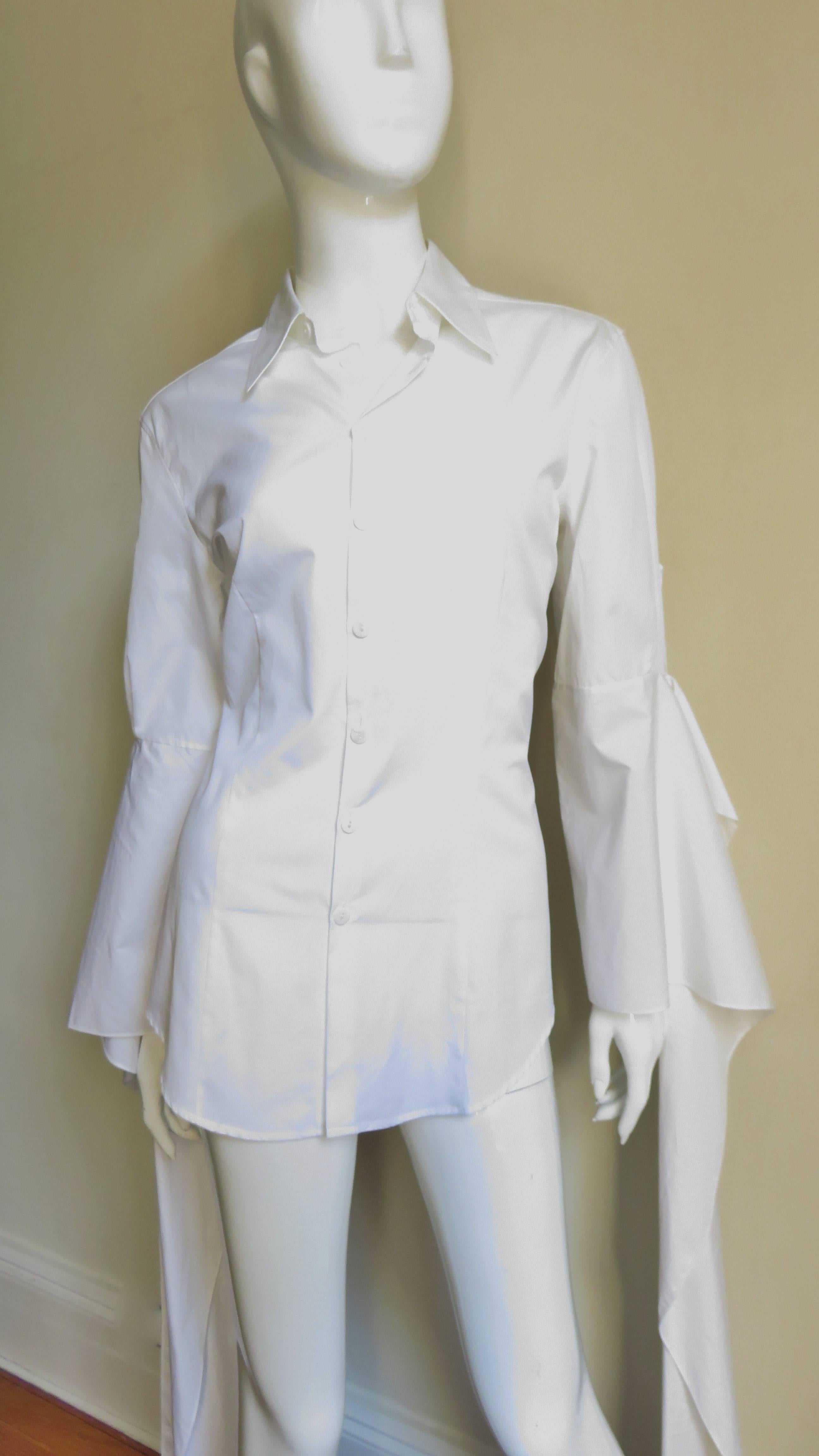 A dramatic white cotton shirt from Jean Paul Gaulier.  It has a mother of pearl button up front with a shirt collar and long open from the eblow bell sleeves with exaggerated cal length cuffs. Princess seaming makes for a great fit.  Fabulous! 