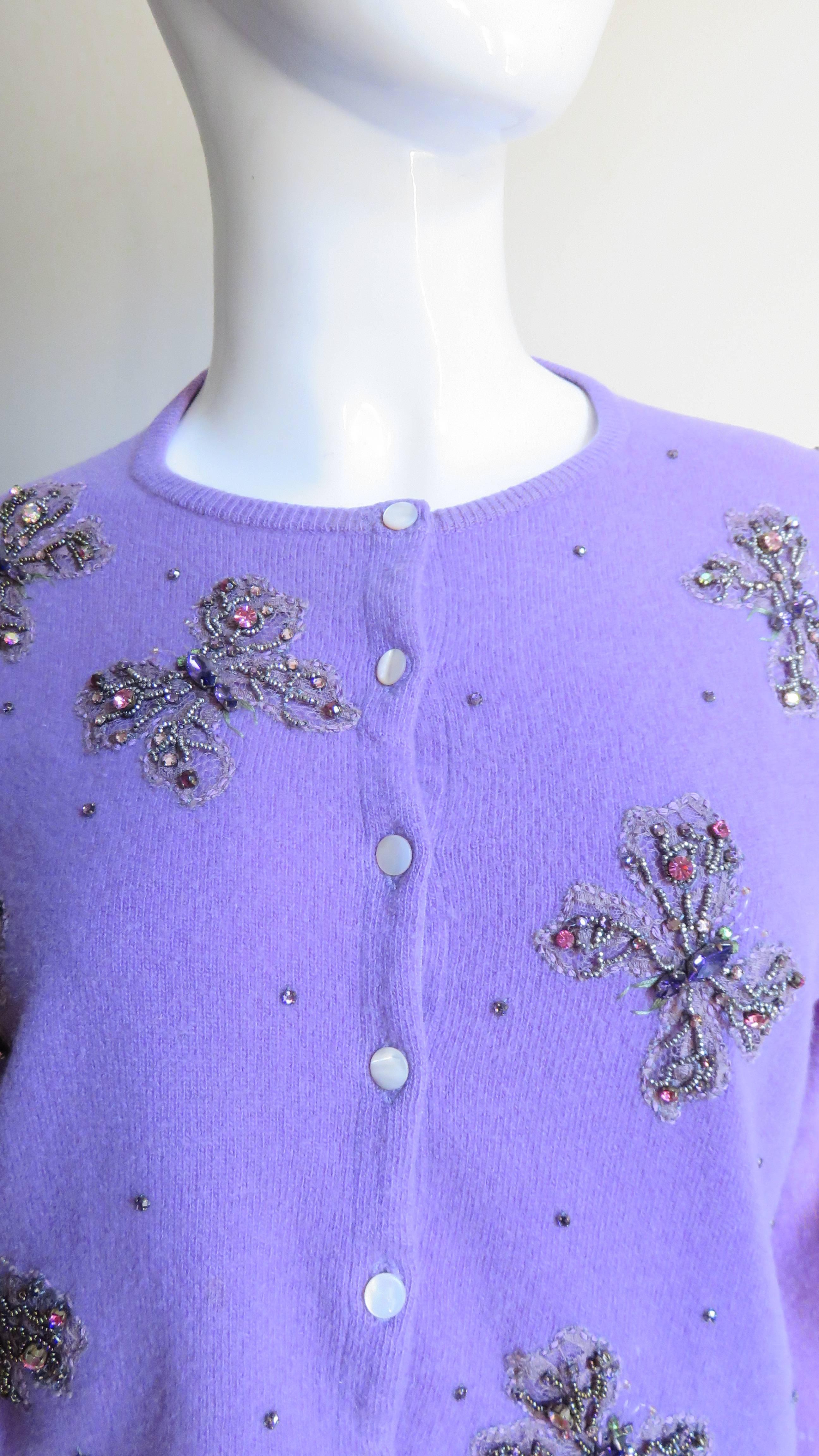 A gorgeous lilac cashmere cardigan sweater from Peck & Peck, Scotland. It has long sleeves, buttons up the front with mother of pearl buttons and is adorned on the entire front and one back shoulder with matching glass seed bead and prong set