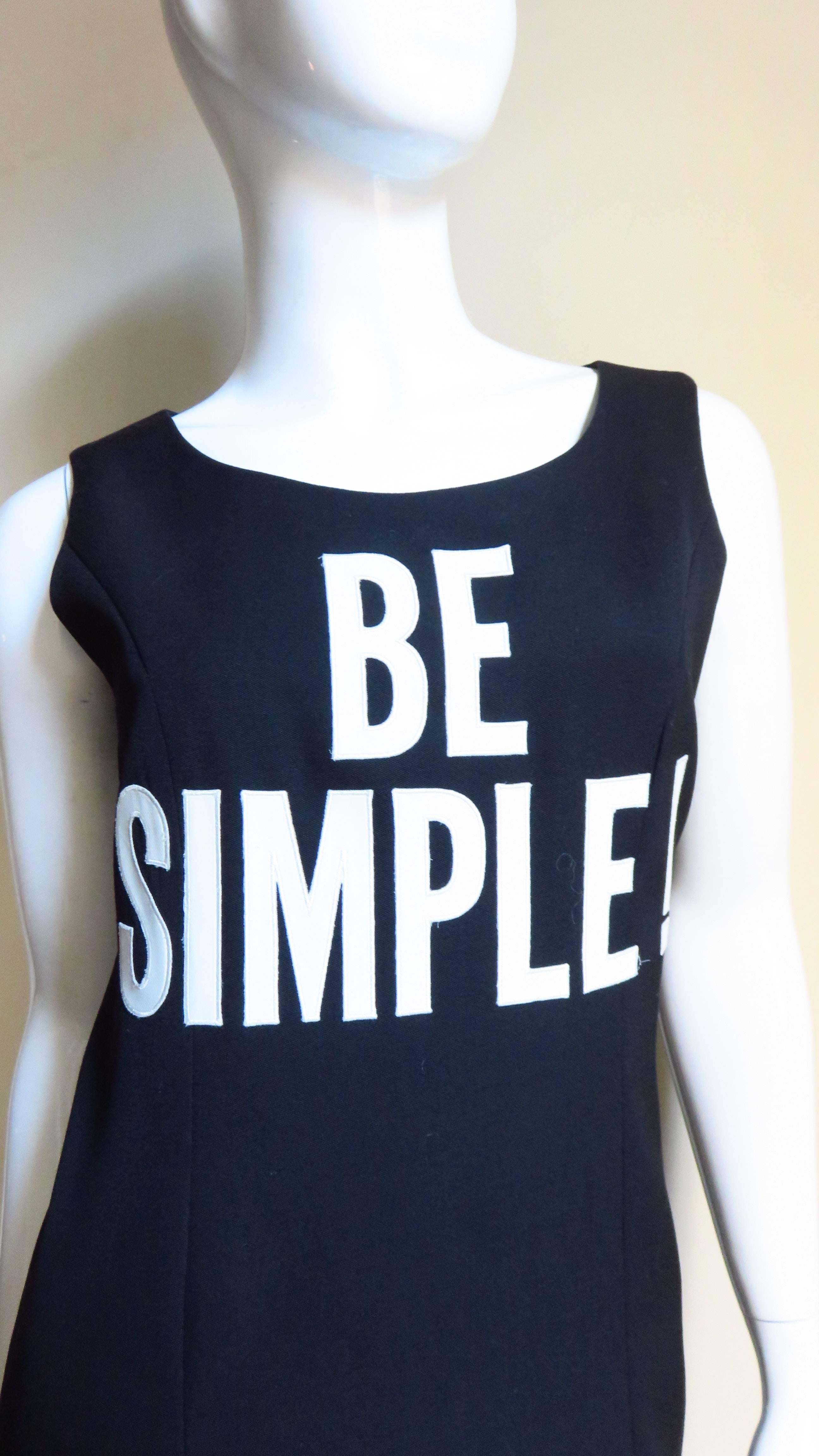 A fabulous dress and jacket set from Moschino Couture in black highlighted with white silk appliqued lettering.  The dress is a simple sleeveless shift with a crew neck and the words 'BE SIMPLE' appliqued on the chest in large off white silk