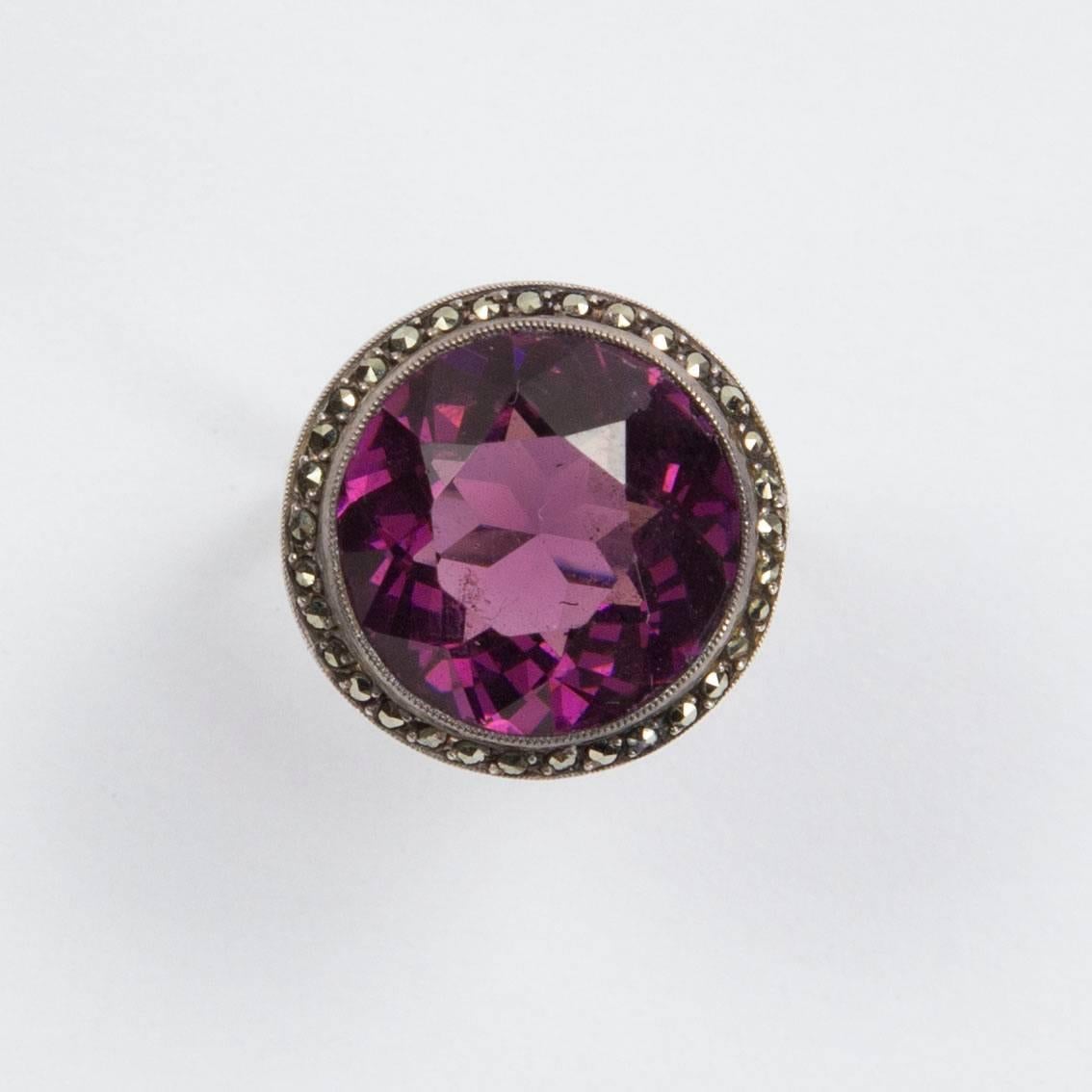 Fabulous Solitaire Ring set with a large round facet-cut faux Amethyst measuring approx. 16mm; surrounded by genuine Marcasite stones; beautifully hand crafted Sterling Silver mounting; Size 7.25; we offer complimentary ring re-sizing; Vintage Art