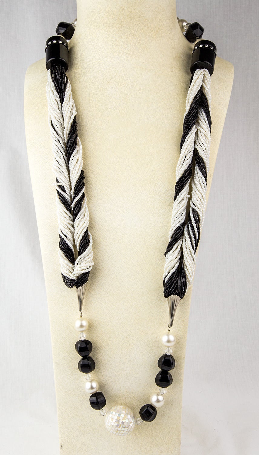 Ce collier noir et blanc exceptionnel est composé d'une combinaison de perles en celluloïd, de perles de rocaille, de perles noires tubulaires incrustées d'un cercle de strass, d'une perle boule de discothèque, de fausses perles, de cristaux et