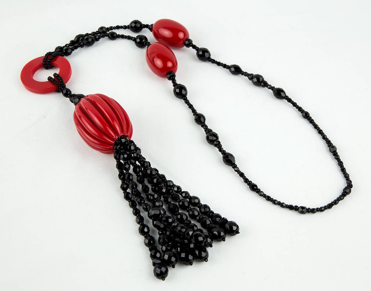 Stunning Red Celluloid and Black faceted Jet Bead Statement Necklace; reminiscent of the Flapper era, necklaces of the Roaring 1920s! Measures approx. 26” long (no clasp) not including the tassel. Red celluloid ring and assorted faceted black jet