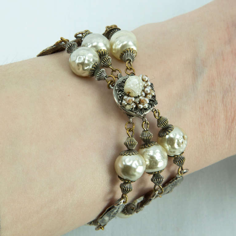 Mid Century Modern Signed Miriam Haskell, beautifully handmade triple strand bracelet with Faux Baroque Pearls inter-spaced with Silver tone leaves. The clasp has a baroque pearl in the center framed by seed pearls; silver tone setting and measures