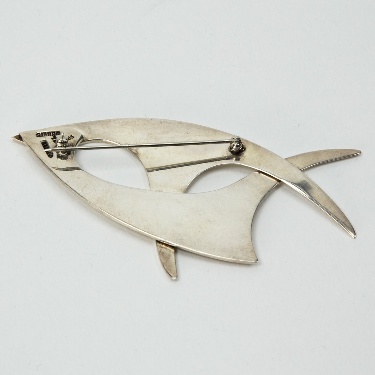 A Striking Iconic Modernist Abstract Fish pin by the famous Sierra Mexico Silversmiths. Beautifully crafted in sterling silver; measuring approx 4” x 2”. Fully hallmarked: MEXICO SIERRA 925 TD C1960s. Add a little flair to any outfit!