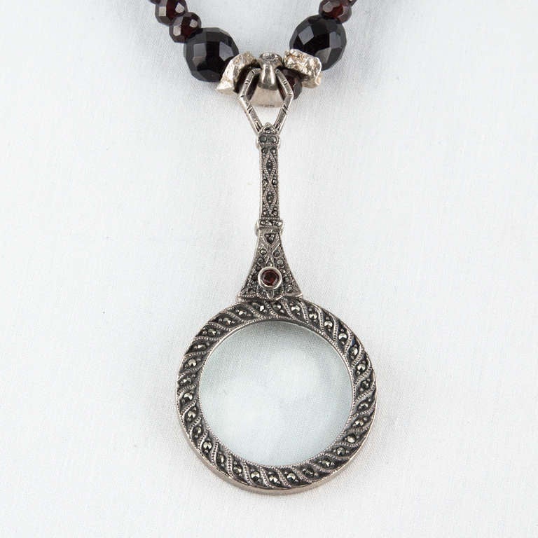 Stunning Facet Onyx and Garnet Beads Necklace, inter-spaced with S/S rondelles, suspending a Hand Magnifier Pendant crafted in Sterling Silver and set with Garnet and Marcasites. Approx length: 28” plus 3” hand pendant. 