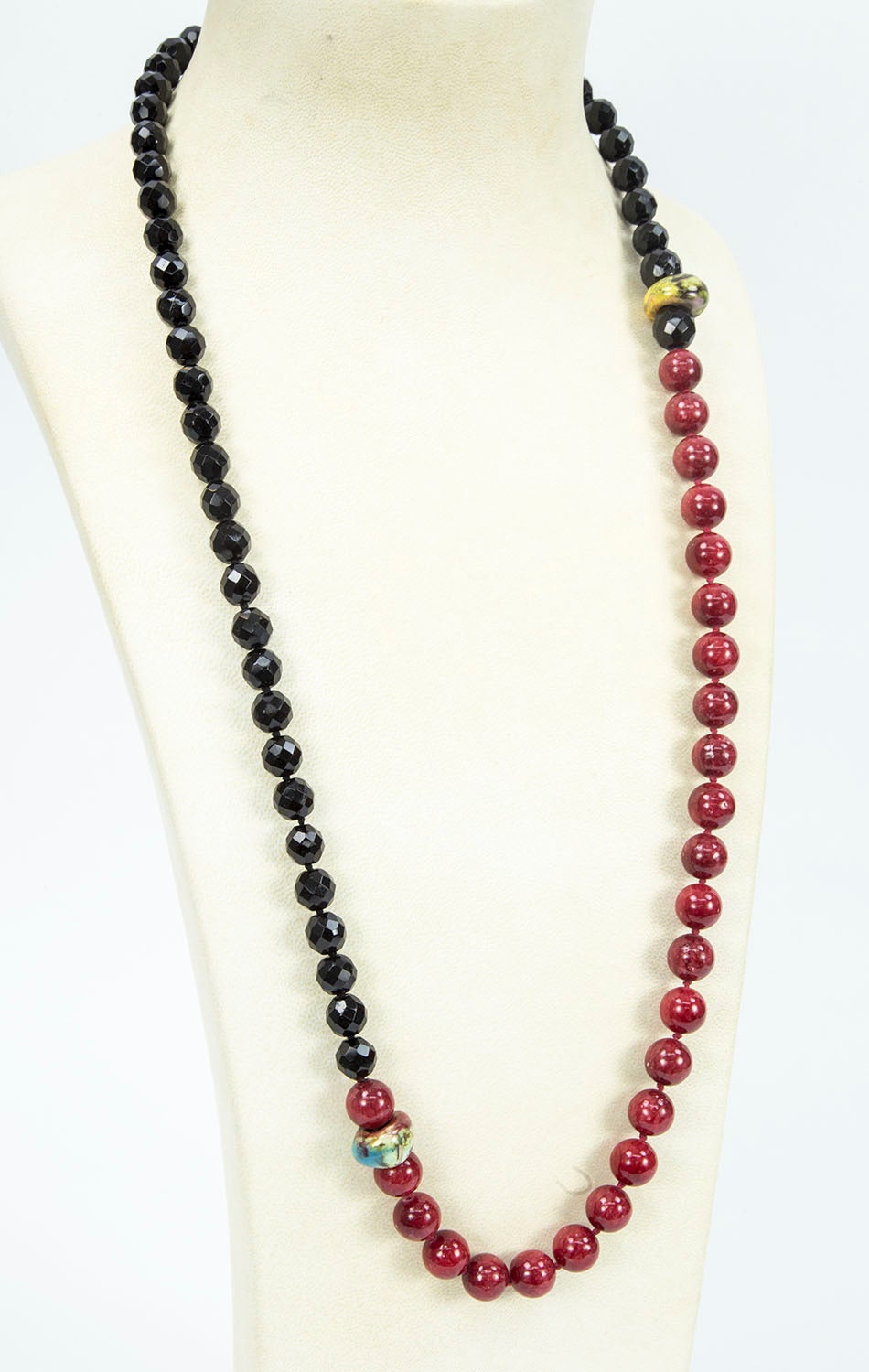 Unique Black Jet and Red Agate Necklace; hand knotted with matching color silk threads; enhanced by 2 Fimo beads; faceted black jet beads are approx. 10mm and the red agate beads 12mm-12.5mm; strand measures approx. 34” long. Add Pizzazz and style