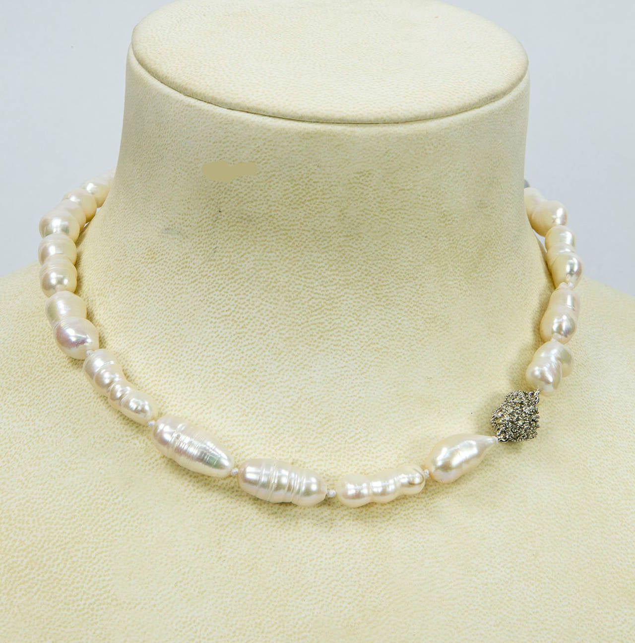 Unique shaped large white Freshwater Baroque Pearl Necklace; hand knotted held by a CZ encrusted Heart magnetic clasp; Pearls are approx. 16mm-21mm (most pearls measure 21mm long); strand measures approx. 16” long. Go anywhere in style with this