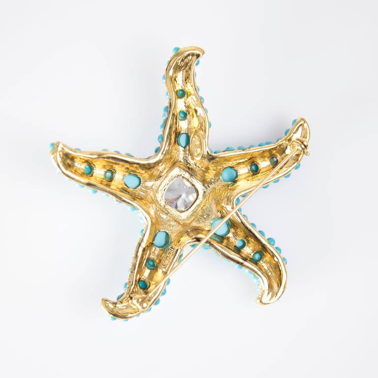 Beautiful pin featuring a Golden Star Fish encrusted with glass Turquoise blue cabochons and a striking blue Sapphire rhinestone in center. Signed: KJL; measuring approx.  3