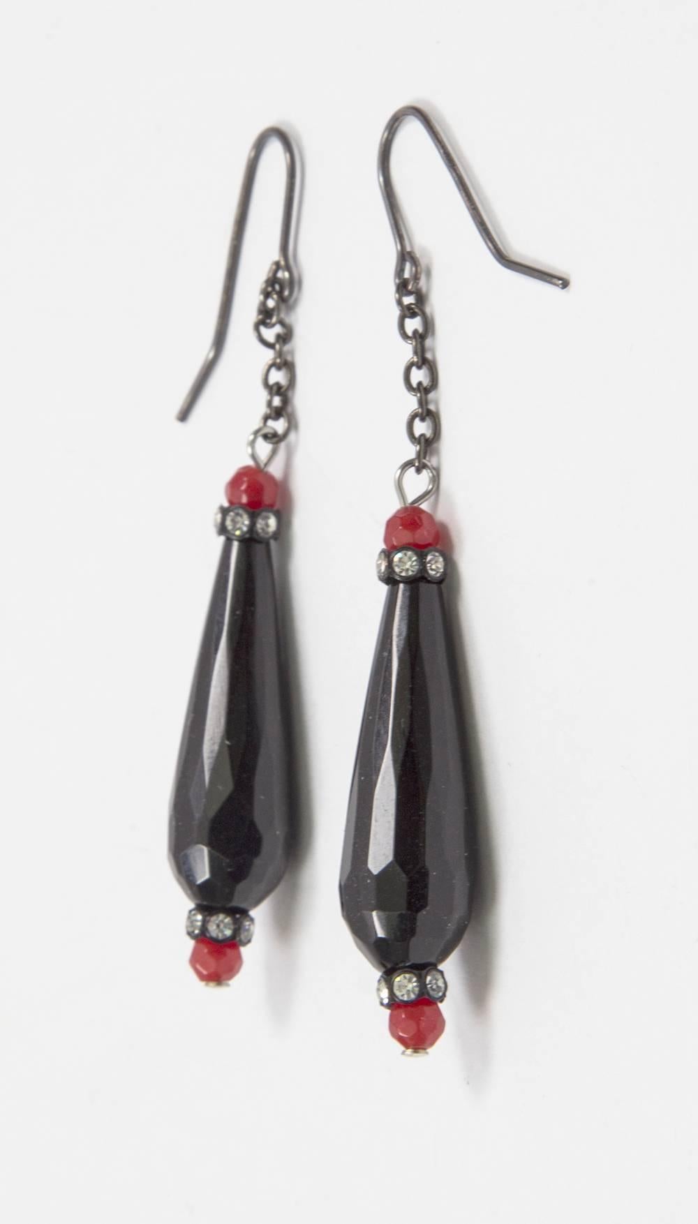 Soft faceted sheen Black Jet Dangle Earrings accented by faceted red and Sparkling CZ stones, each suspending a faceted elongated teardrop shaped Jet glass bead, measuring approx. 1.5” each in length; approx. length of earrings: 3”. Chic and