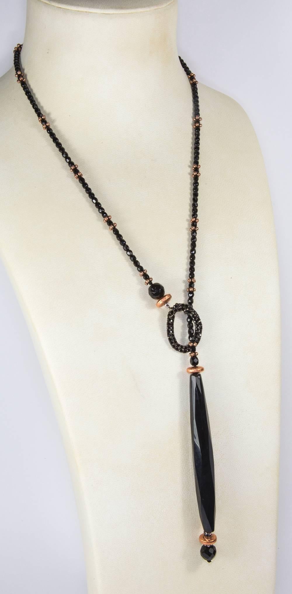 Soft faceted sheen Black Jet Lariat Necklace, accented by copper rondelles and sparkling CZ stones, suspending a large faceted elongated teardrop shaped Jet glass bead, measuring approx. 4” in length; approx. length of necklace: 24”. Vintage beads