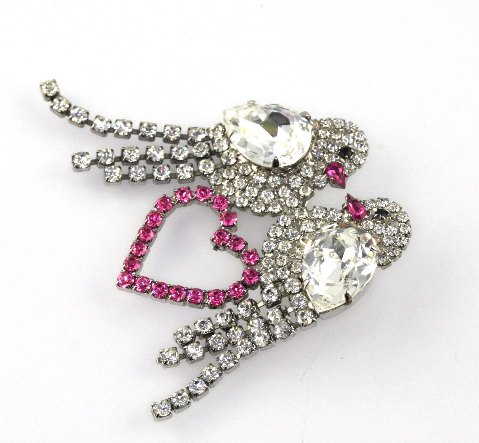 Vintage Butler & Wilson Rhinestone Lovebirds Heart Brooch Pin brooch featuring two clear crystal chaton rhinestone birds with trailing rhinestone fringe tails, perched atop a pink rhinestone heart; large pear shaped clear rhinestone wings, pink pear