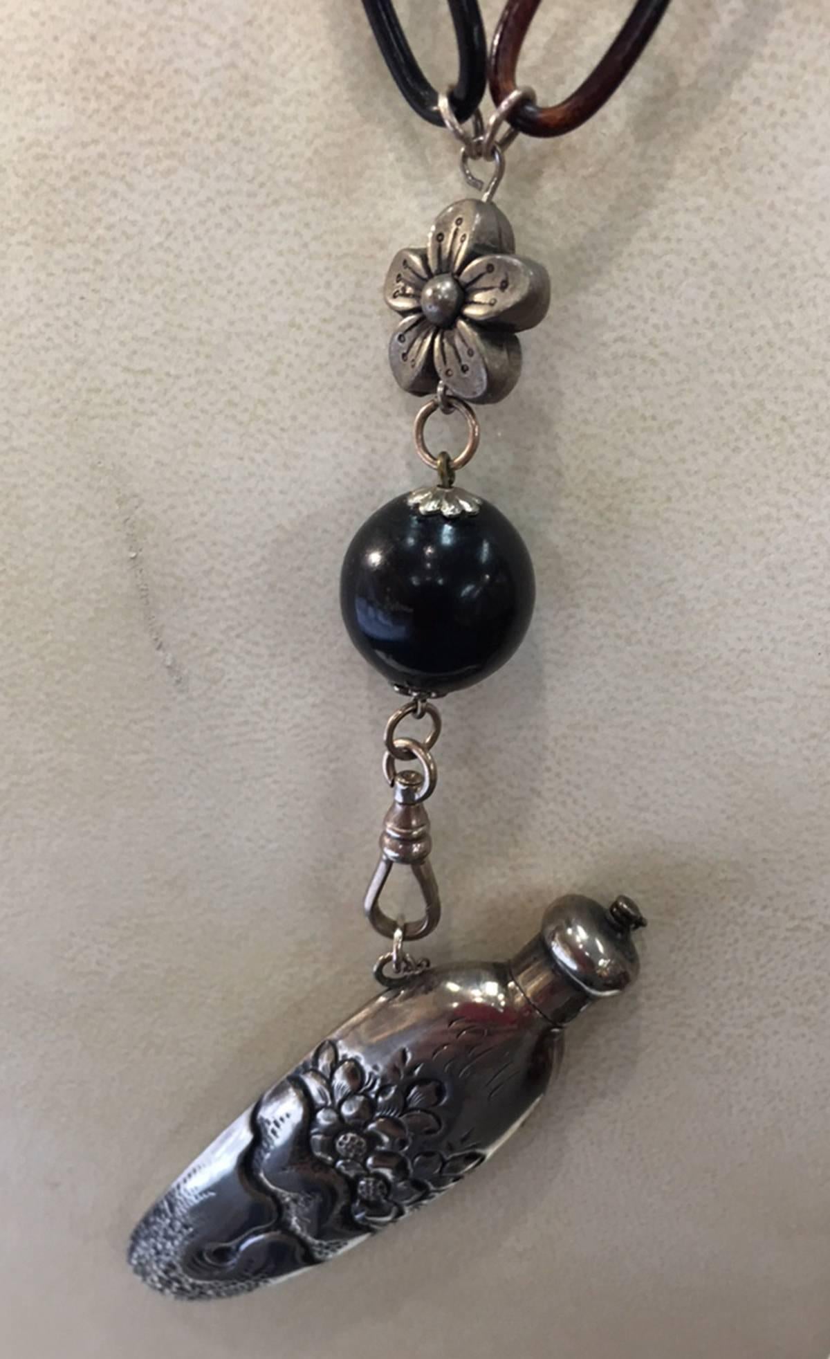Simply Fabulous! Rare wearable sterling silver hand chased scent flask, in its original state; suspended from a divine Bakelite necklace; approx. 24” long.  Functional perfume holder with a threaded top that closes securely and is held by a chain;