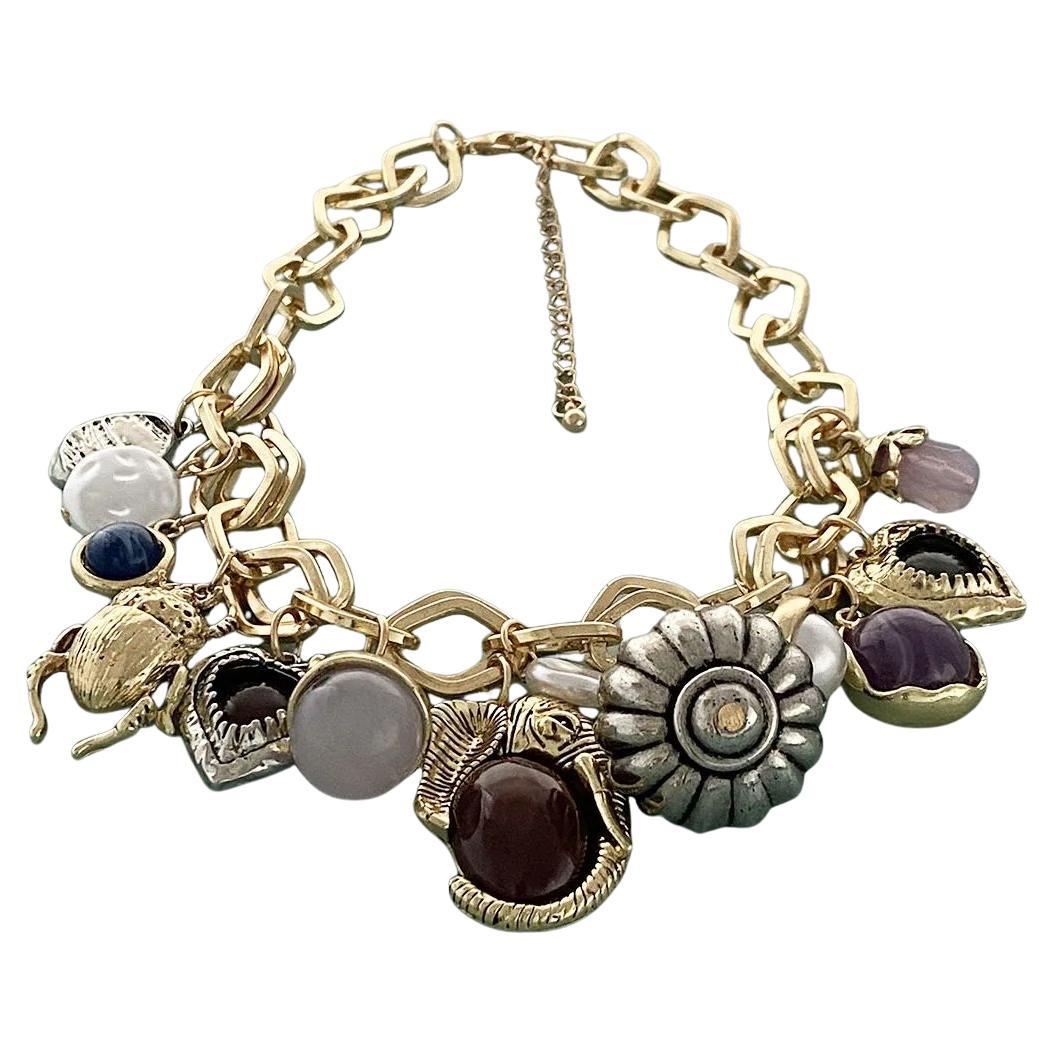¡Sencillamente impresionante! Collar vintage de eslabones abiertos con múltiples dijes en tono dorado. Rebosante de encantos múltiples. Suspendida de una cadena de eslabones abierta en tono dorado. Los abalorios y las cuentas varían de tamaño. Mide