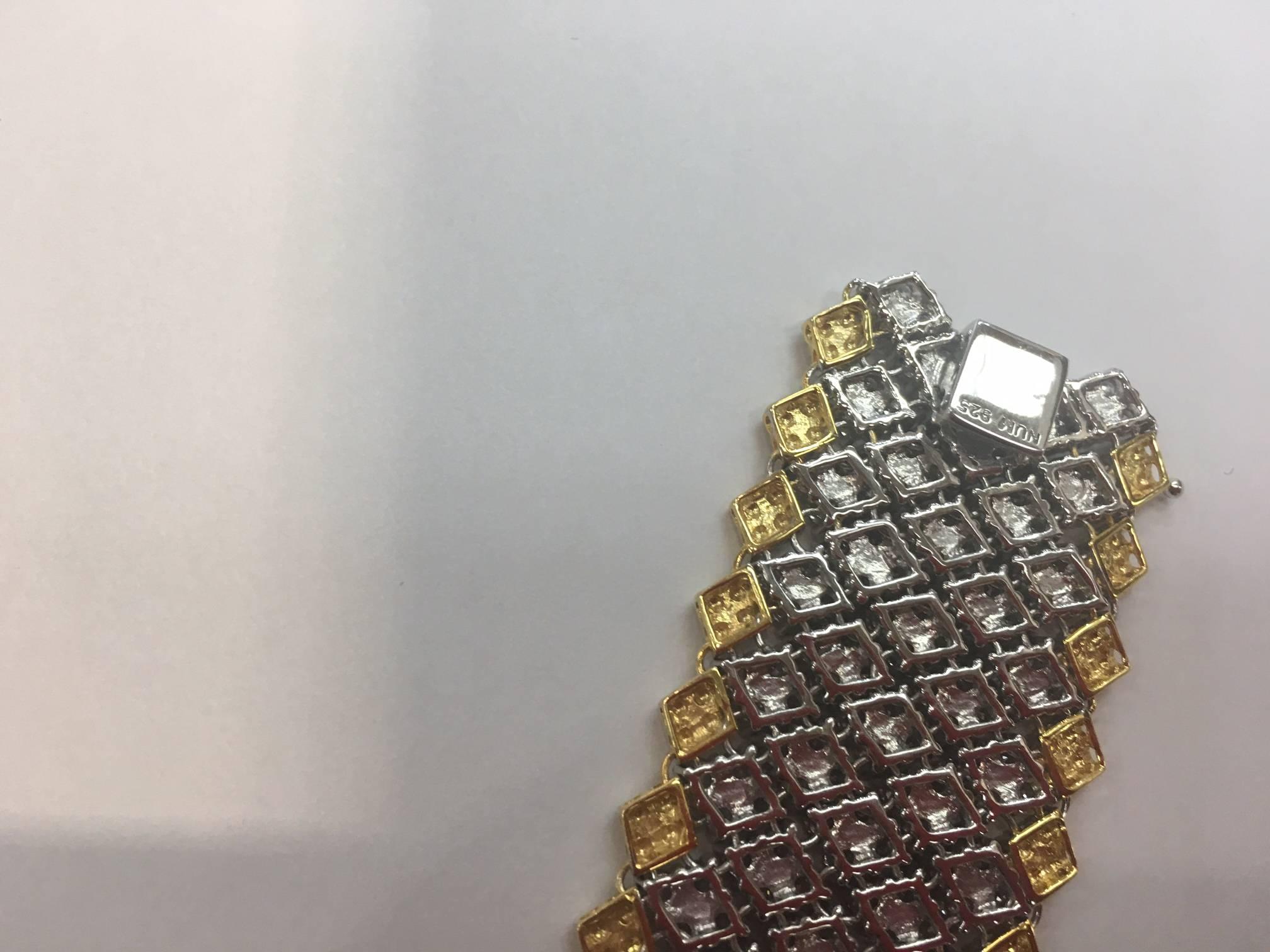 Beautiful bracelet featuring five rows of Diamond shaped encrusted Swarovski crystal; gold shaped edged pattern. Matching push clasp also set with a CZ crystal; approx.7 inches long x 1.25 inches wide. Marked: 925; A Show Stopper…. Illuminating your