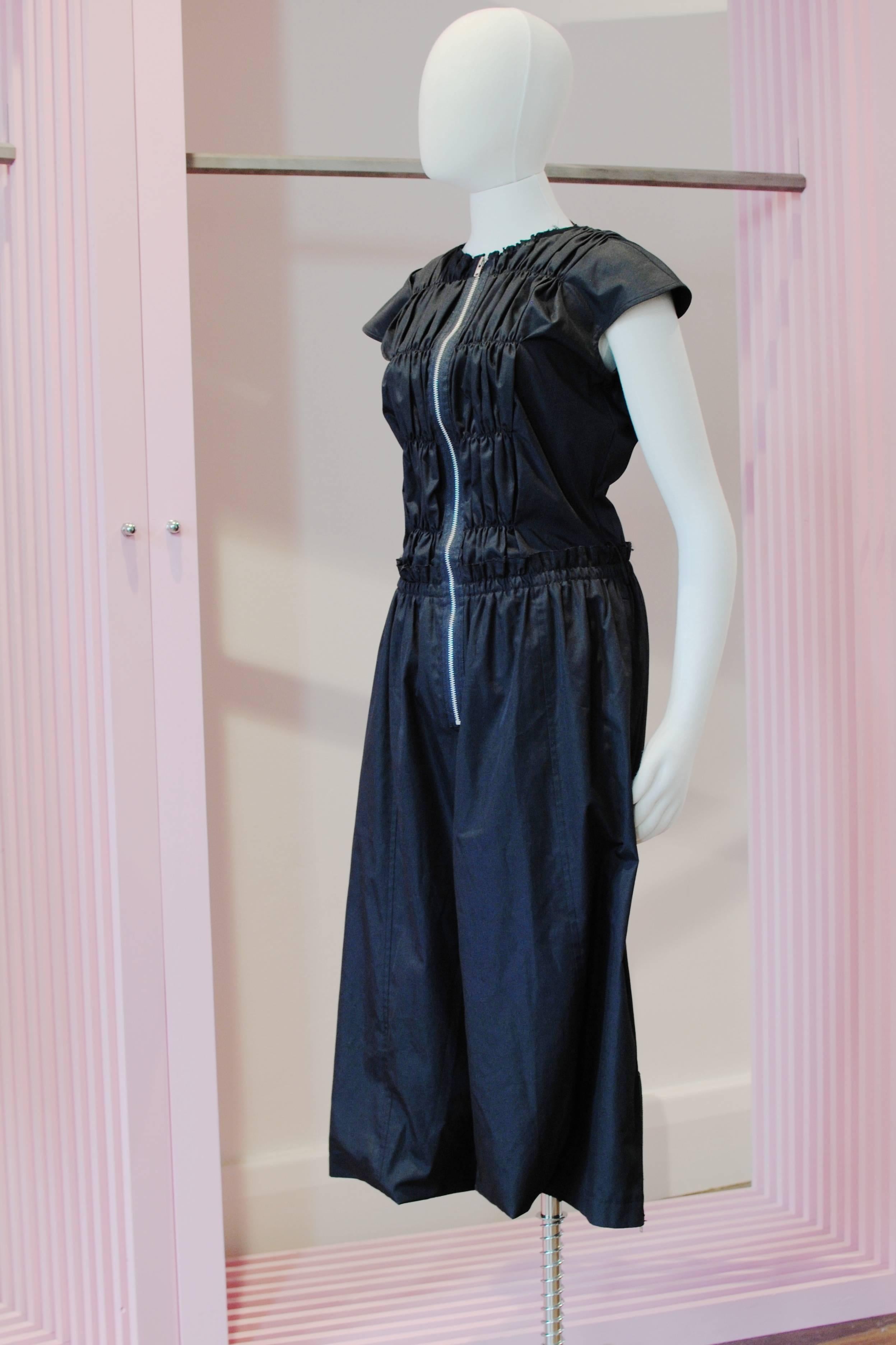 COMME des GARÇONS black samurai jumpsuit from the 2002 Spring/Summer collection. It features a ruched chest and back, front zip fastening, cap sleeves, two waist pockets, belt loops and two slits at the base for the legs to go through with side