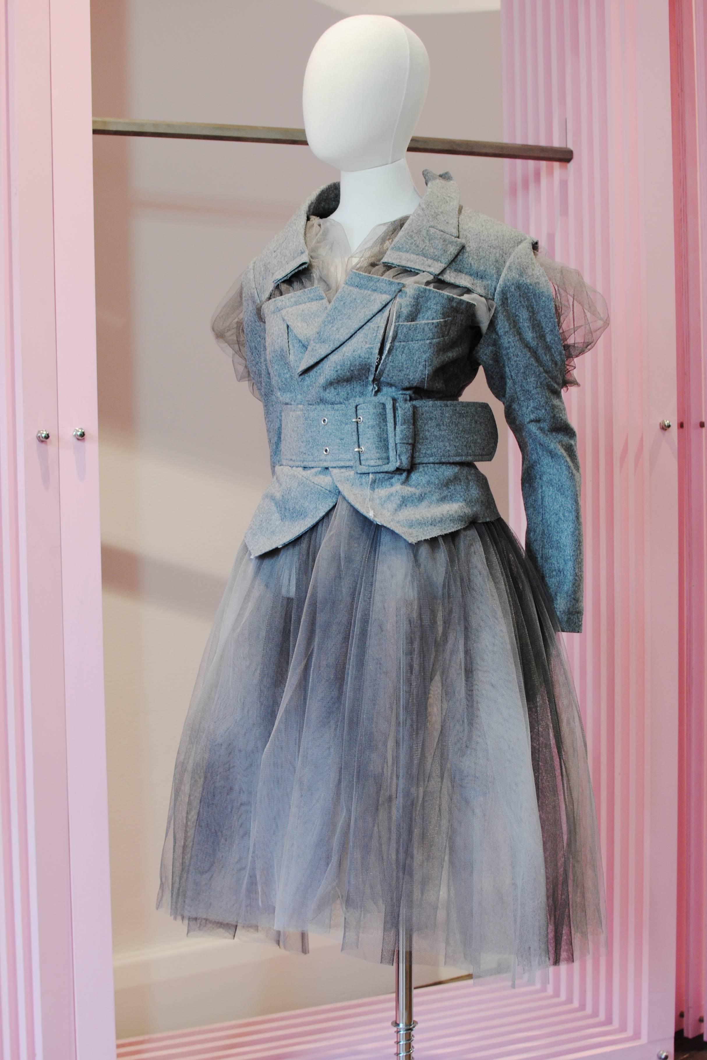 COMME des GARÇONS deconstructed grey tulle jacket dress from the 2007 Spring/Summer collection. It features a grey wool jacket with belt which is cut away in sections to reveal the layers of tulle underneath.

Size — Small
Shoulder — 45