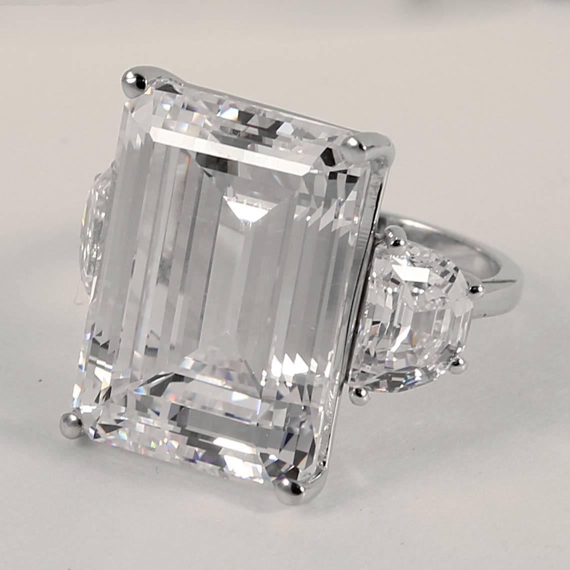 Magnificent faux 25 carat rectangular step cut diamond made of the finest hand  diamond-cut cubic zircon set with half moons either side in white gold. This ring has an amazing brilliance and fire. Measures 1inch long and 3/4inch wide.
Free sizing.