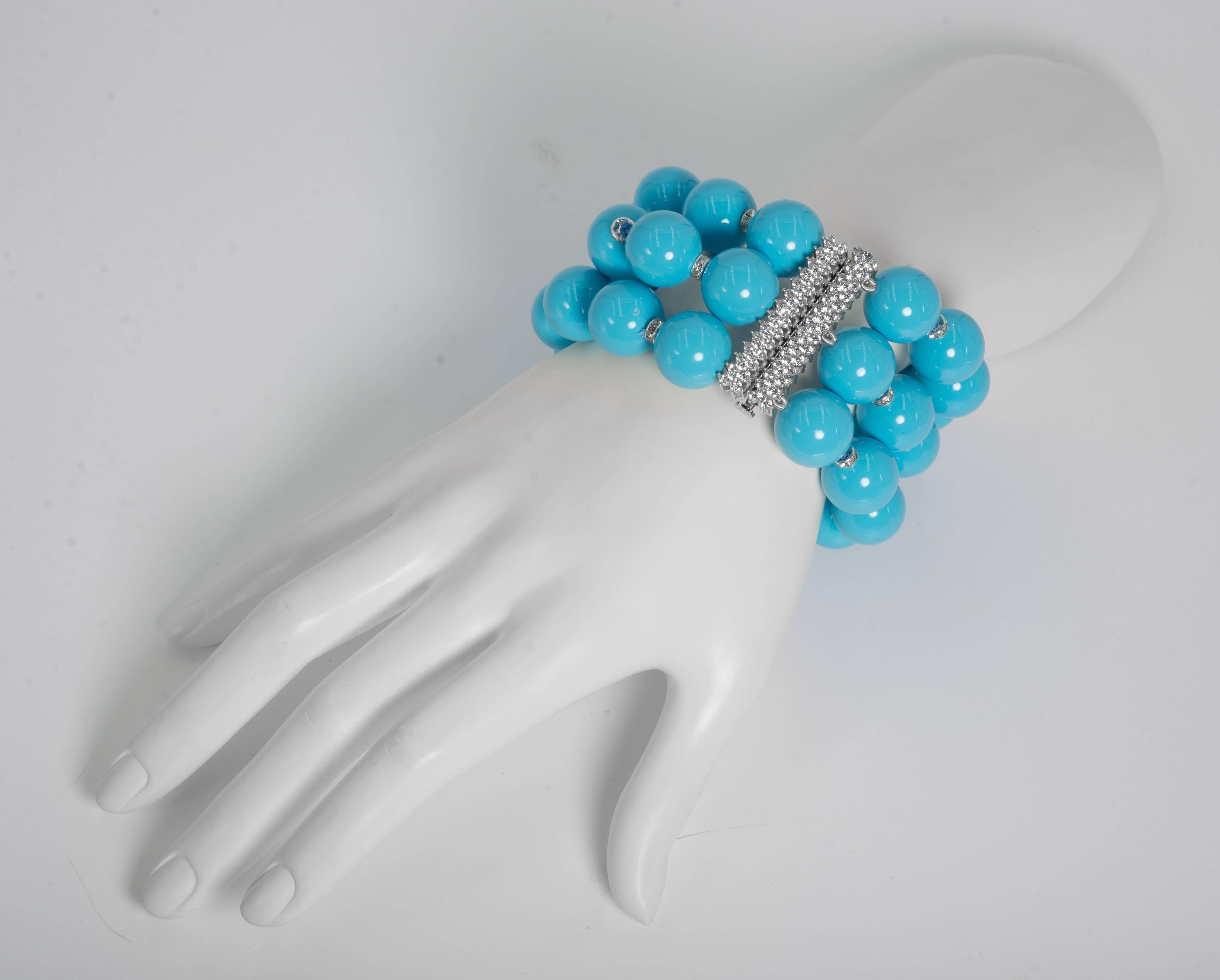 Three strands of 20mm faux turquoise  beads interspersed with crystal rondels silk knotted and strung attached to a cubic zirconia sterling fine jewelled clasp. The bracelet measures nine inches long for the height of the 20mm beads and  is two