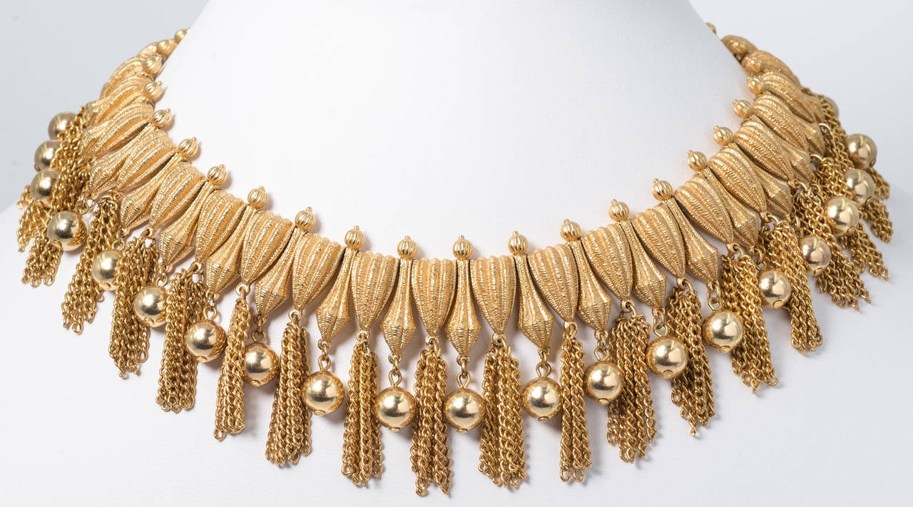 1960s Chic Tasseled Fringe Florentined Gilt Flexible Necklace and Earclips.
The necklace is fringed all the way around the neck and has an adjustable clasp so it may be worn from 13'' to 16'' long. The depth of the necklace is 2 inches.
The