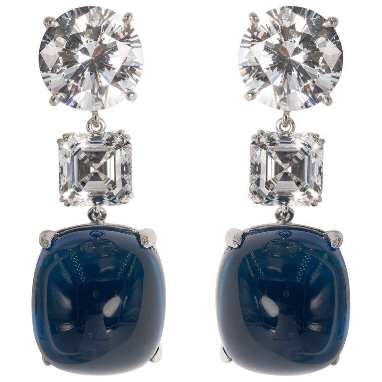 Amazing faux diamond large cabochon sapphire earrings. The round tops are  8 carats each diamond weight, the squares are about 4 carats each and the square cabochon faux  sapphires  are about 40 carats each. Rhodium sterling .
Two inches long  Clip