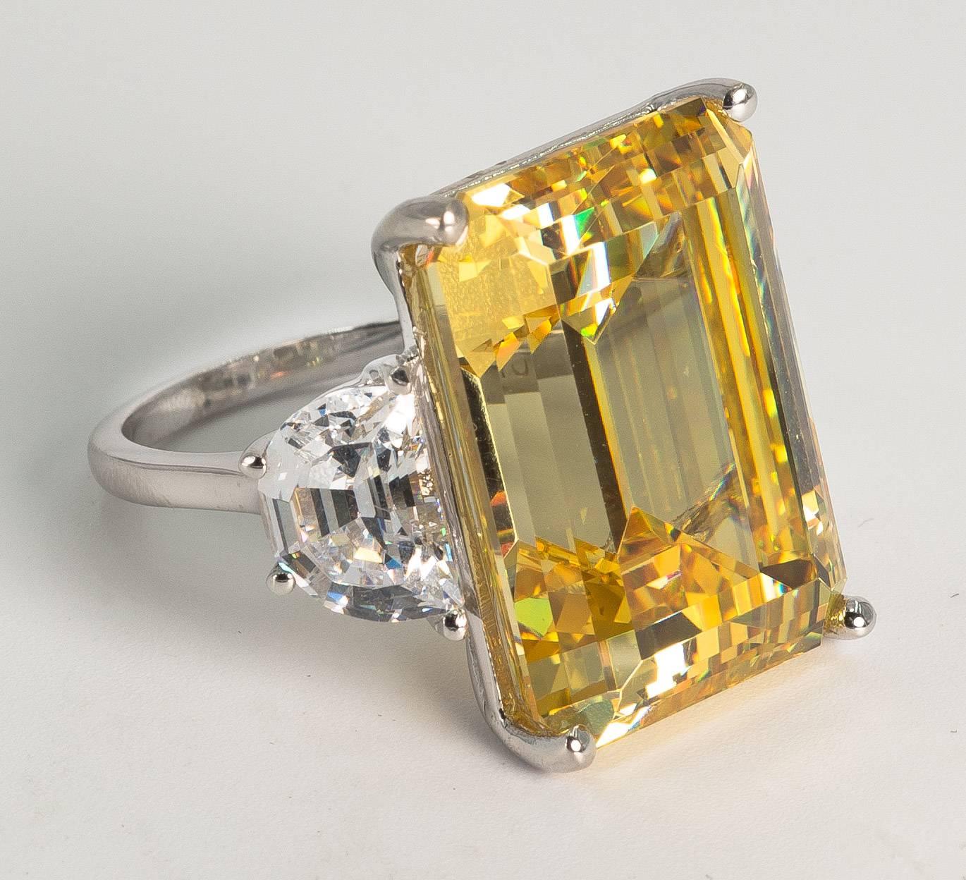 Magnificent faux 25 carat rectangular step cut intense canary yellow diamond made of the finest hand diamond-cut cubic zircon set with half moons either side in white gold. This ring has an amazing intense yellow brilliance and fire. Measures 1inch