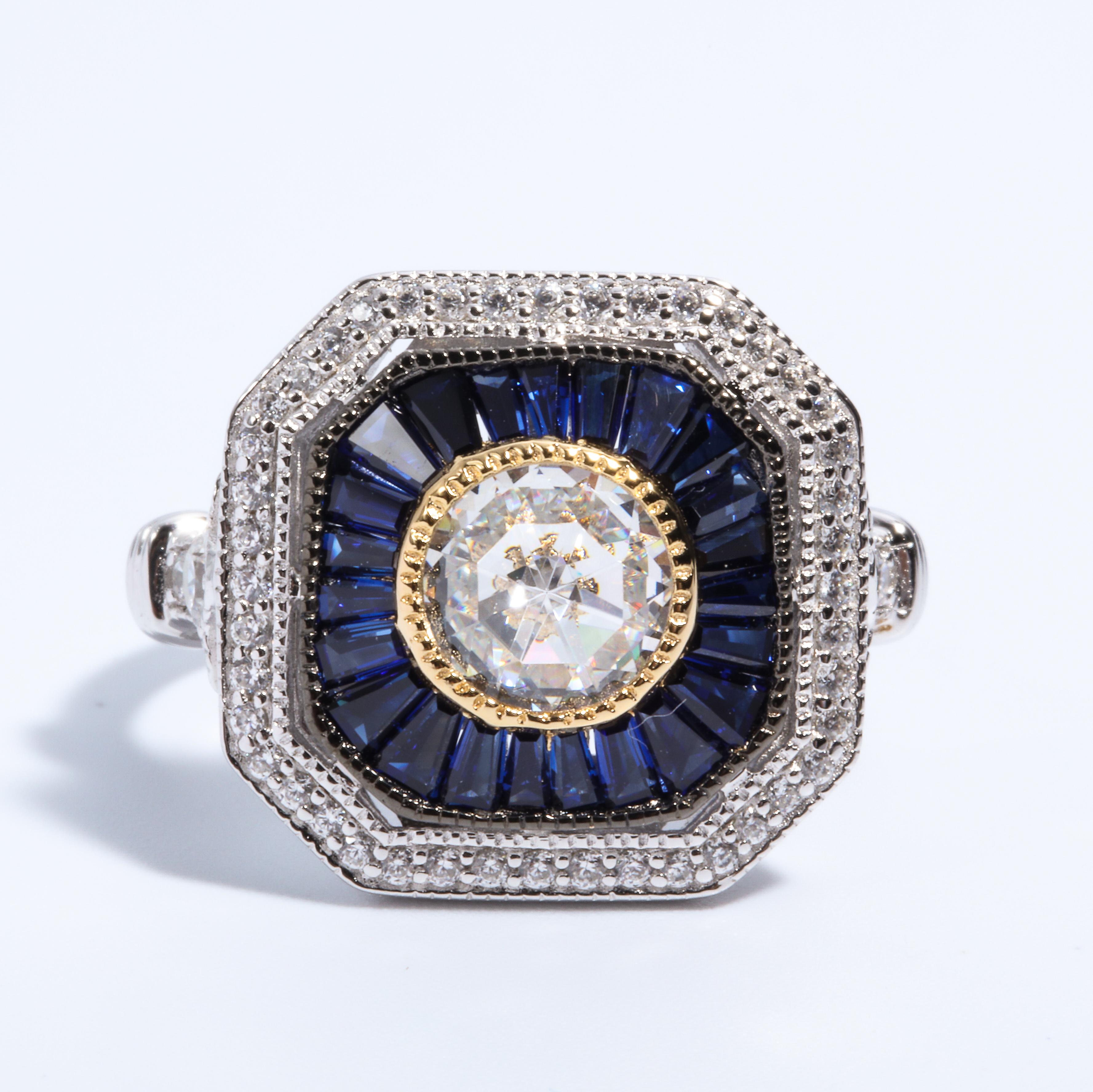 Magnificent Costume Jewelry Art Deco Style Diamond Sapphire Sterling Ring set with a Round CZ Surrounded by Tapered Faux Baguette Sapphires set in non-tarnish Sterling free sizing.
