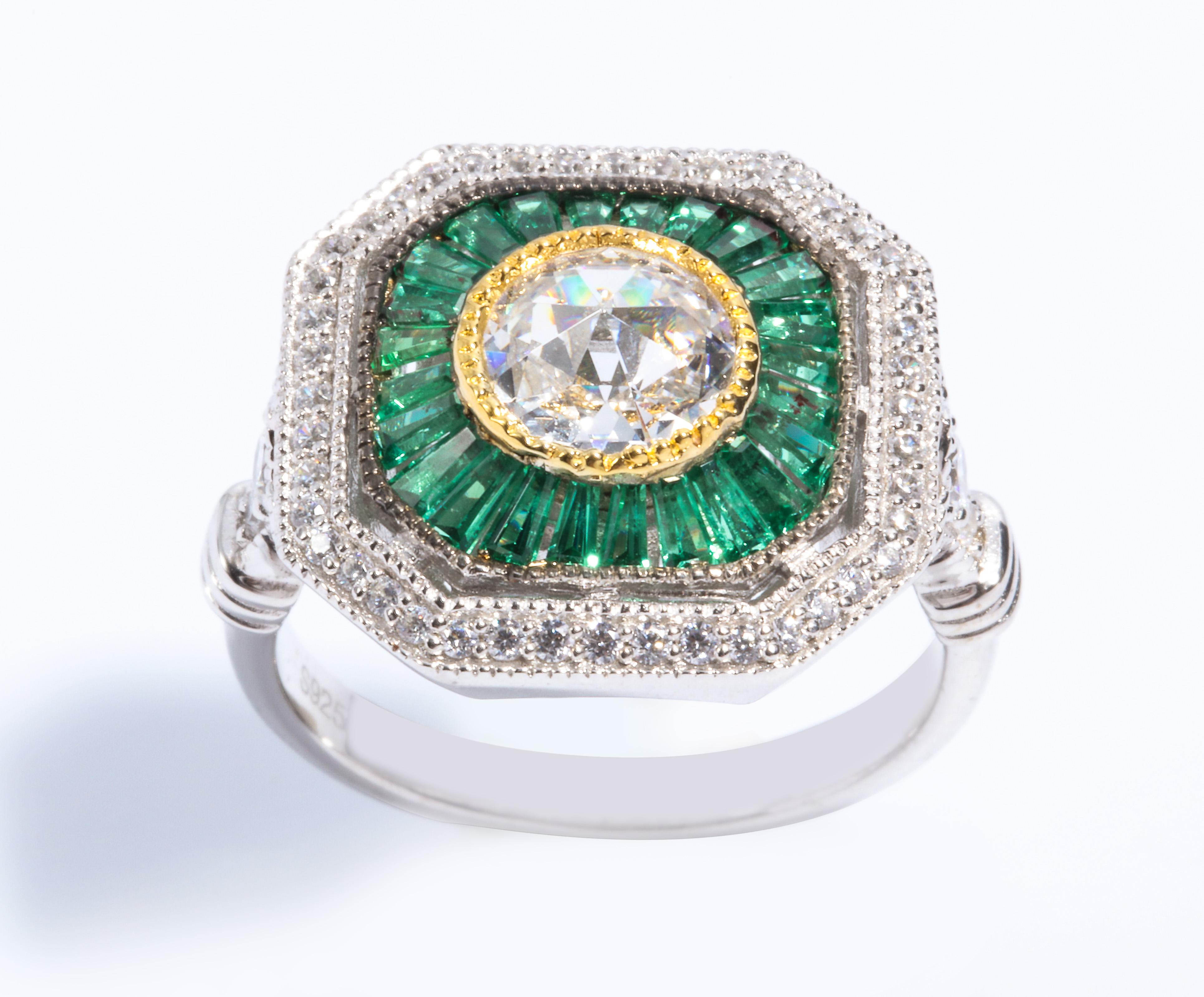 Magnificent Costume Jewelry Art Deco Style Diamond Emerald Sterling Ring set with a Round CZ Surrounded by Tapered Synthetic Baguette Emeralds set in non-tarnish Sterling free sizing.