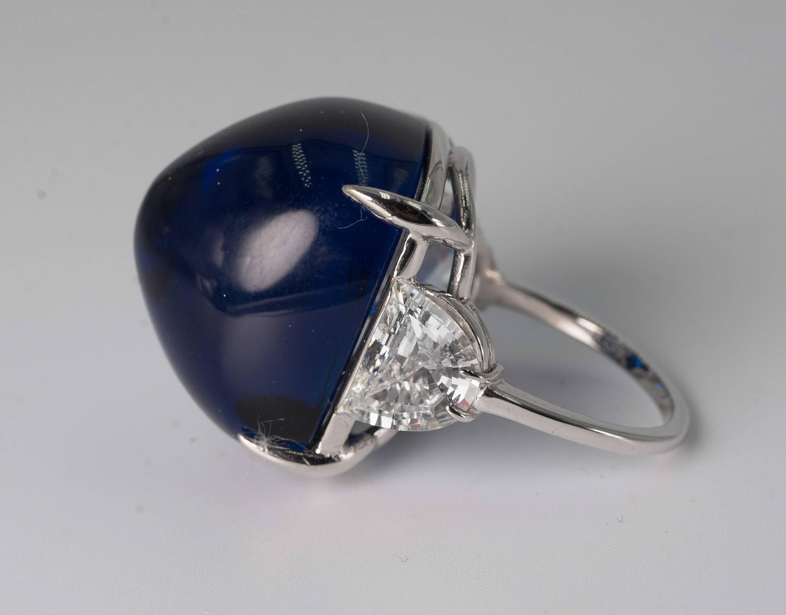 Superb faux French pyramid-cut cabochon Royal Kashmir Blue sapphire half-moon cubic zircon set white gold ring. The faux man-made sapphire has the look of about 40 carats and the side stones about two carat diamond weight each. Faux sapphire