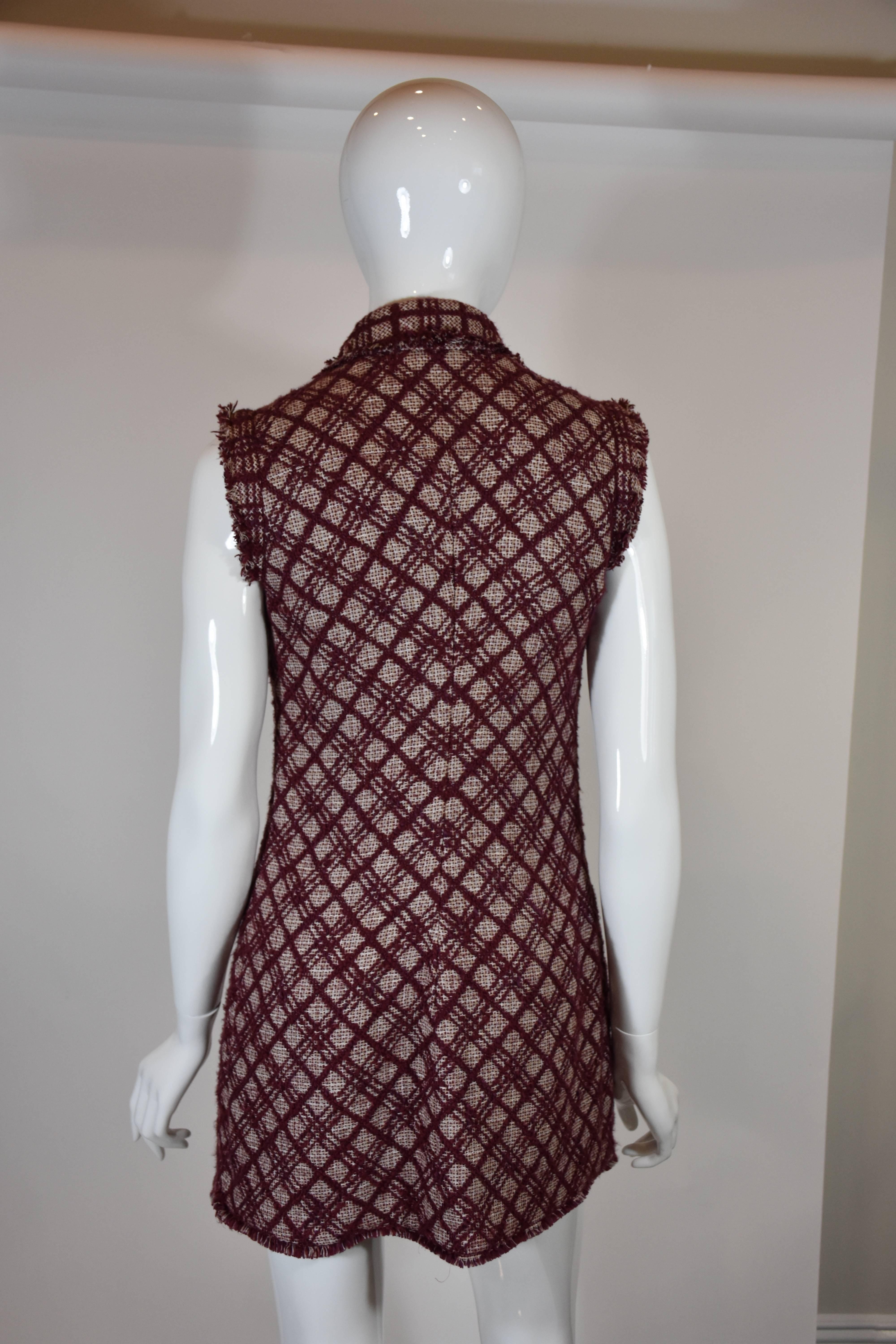 Obsessed with this super soft Chanel vest in burgundy houndstooth. Single button closure. Four open top front pockets. Frayed trim throughout border of front and shoulder. Burgundy silk lined. Made in France. 2008P collection. 82% Cotton. 12% Linen.