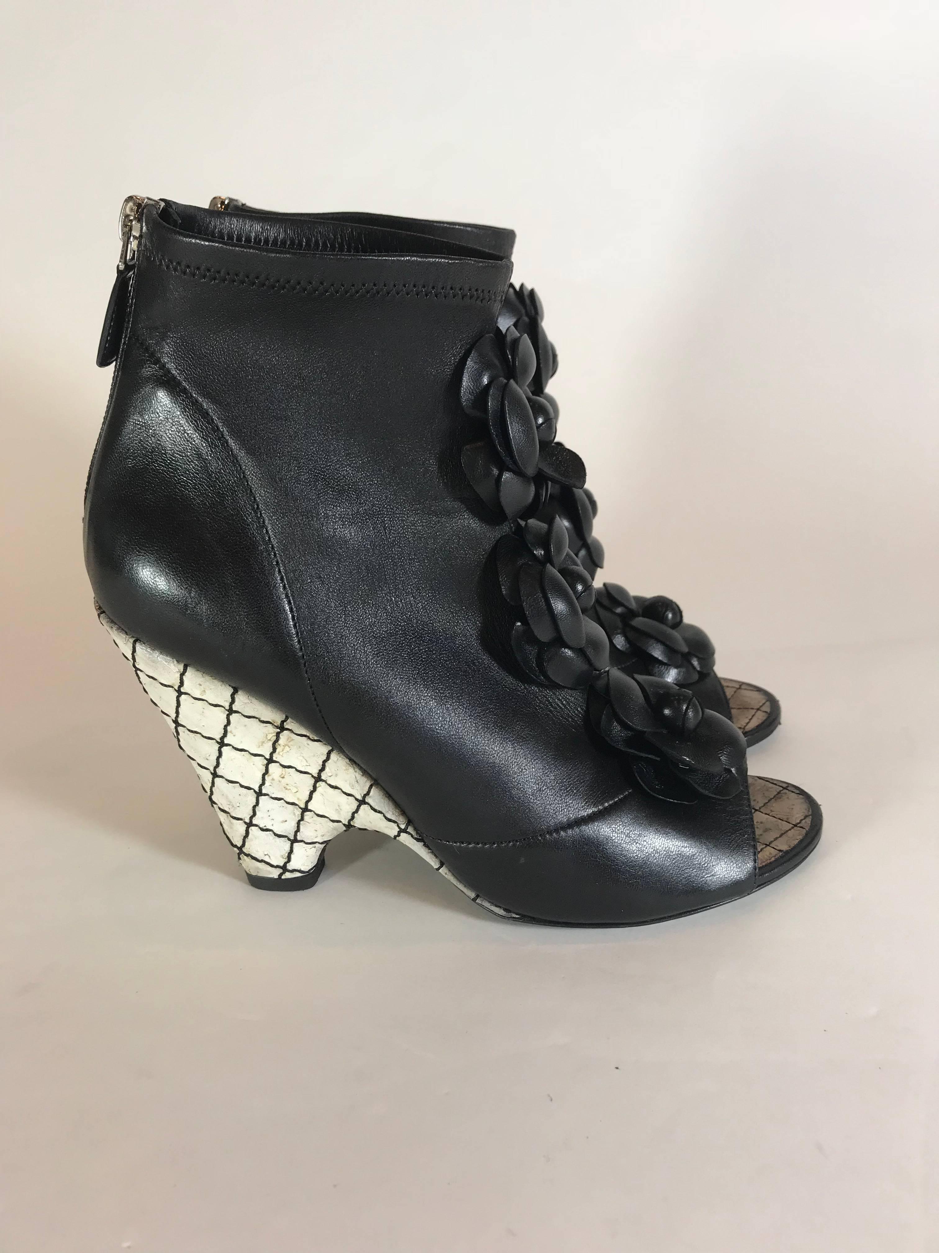 Black leather. Silver-tone hardware. Wedge heel with signature quilted design. Three flower decals on front. Zipper closure at back.