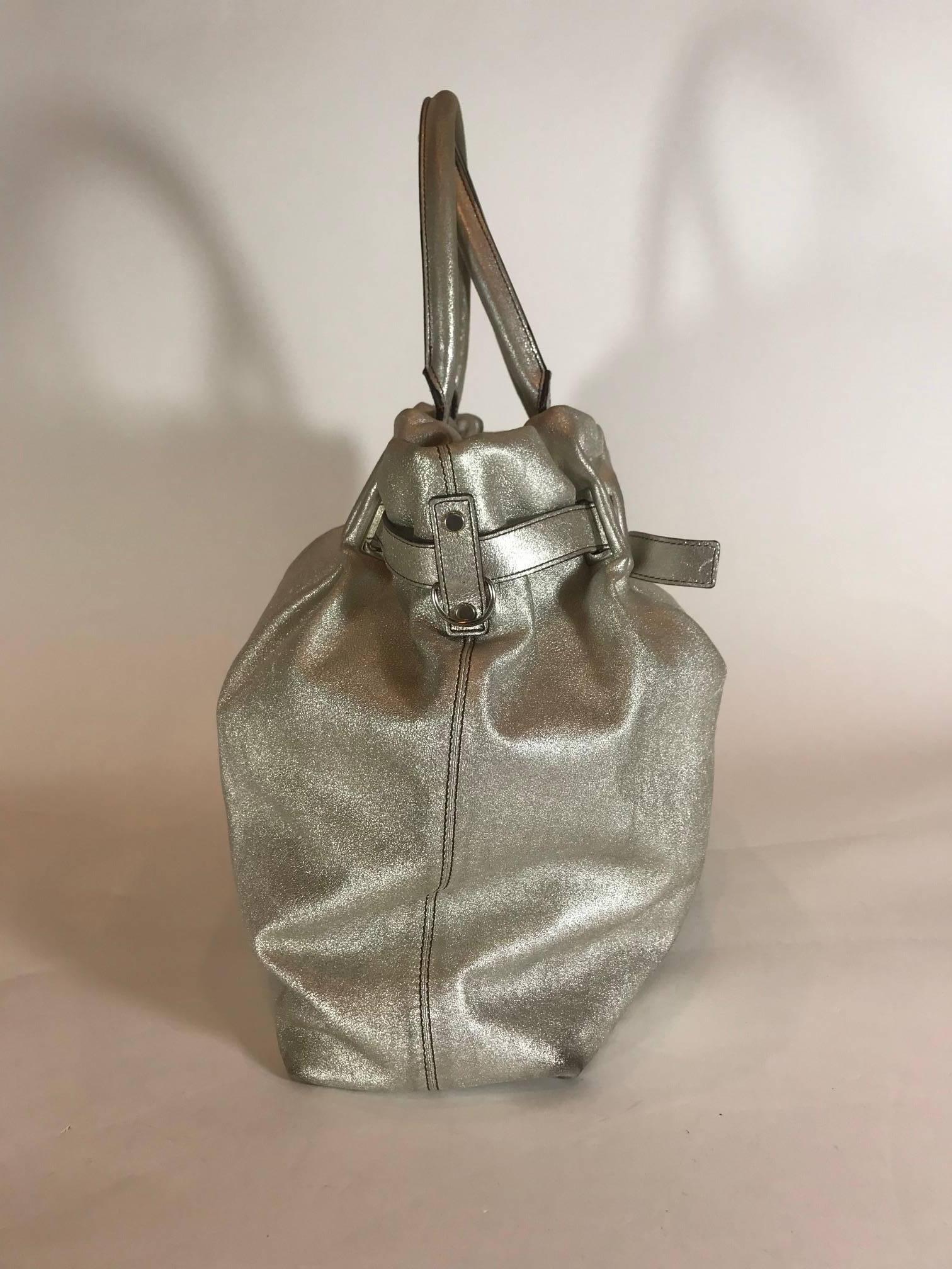 Metallic silver-tone leather. Silver-tone hardware. Rolled shoulder straps. Black jacquard lining. Dual pockets at interior walls; one with zip closure and open top.