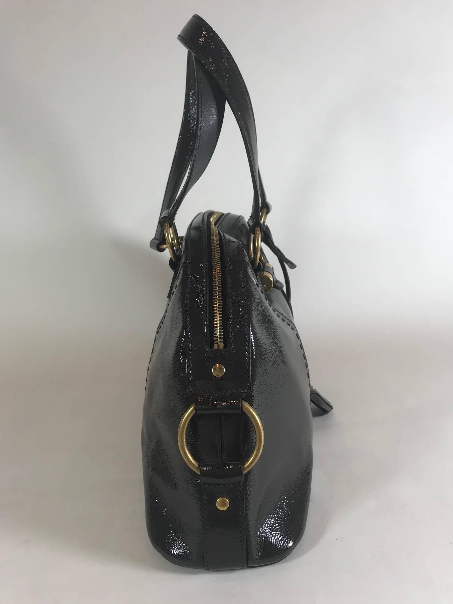 Yves Saint Laurent hit it big with the Muse handbag. This is a grey patent leather bag with gold-tone hardware, black woven interior lining, two pockets at interior walls; one with zip closure and zip closure at top.