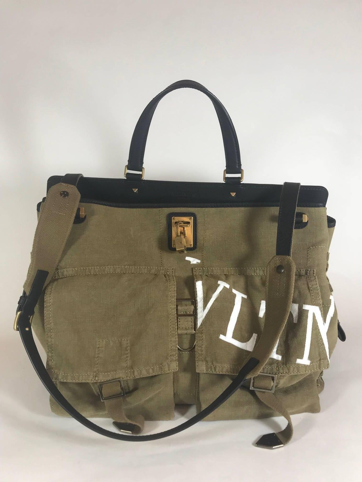 Printed at the front with a white logo, Valentino Garavani's Joylock maxi handle bag is constructed of olive canvas and black grained leather. 
 Brass-tone hardware. Single top handle. Shoulder Strap. Large exterior front pocket. Top handles.
