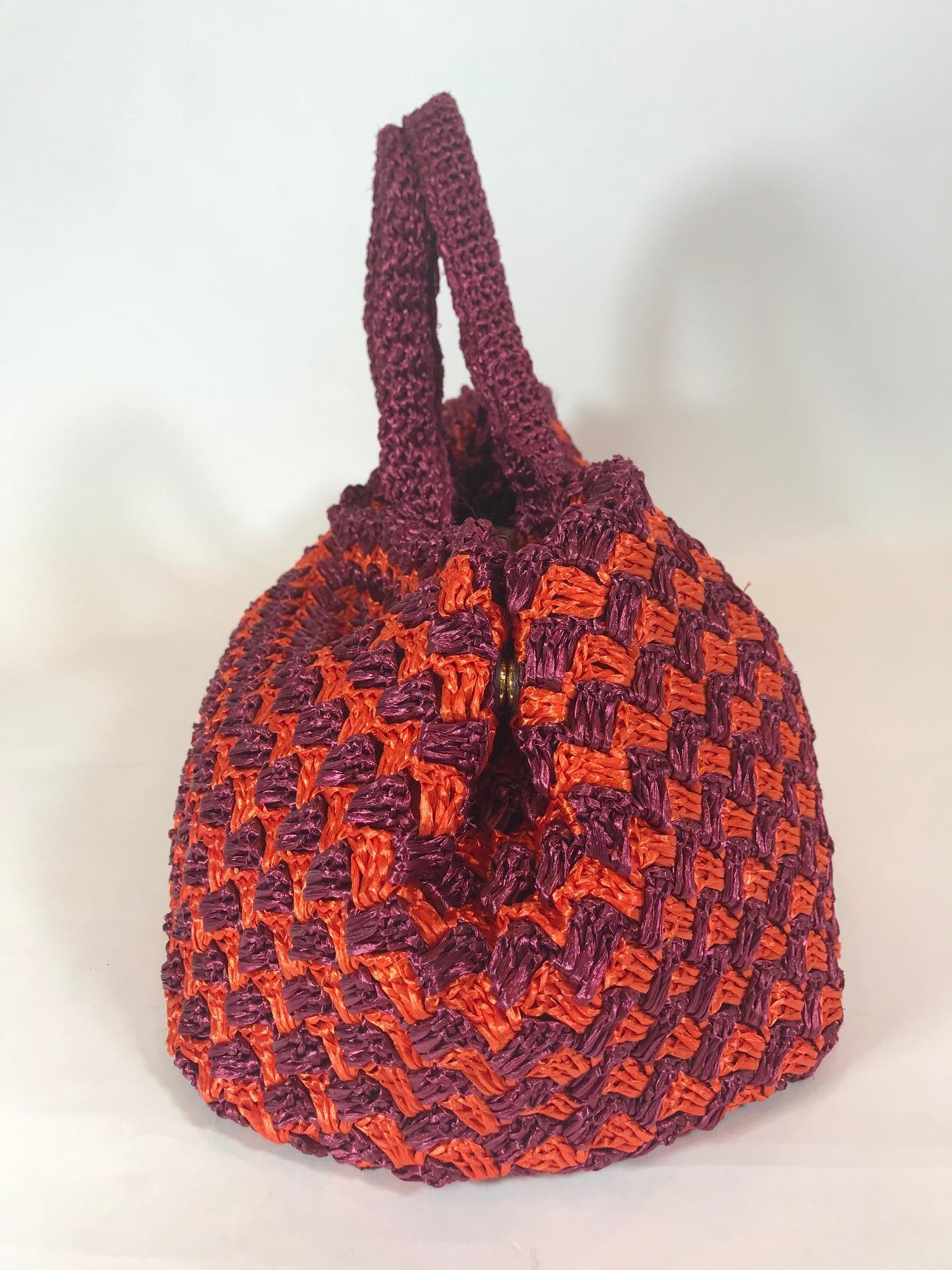  Red and orange crocheted Raffia straw. Gold-tone hardware. Dual flat handles. Snap expansions at sides, red jacquard woven lining, four pockets at interior wall; two with zip closure and open top.
