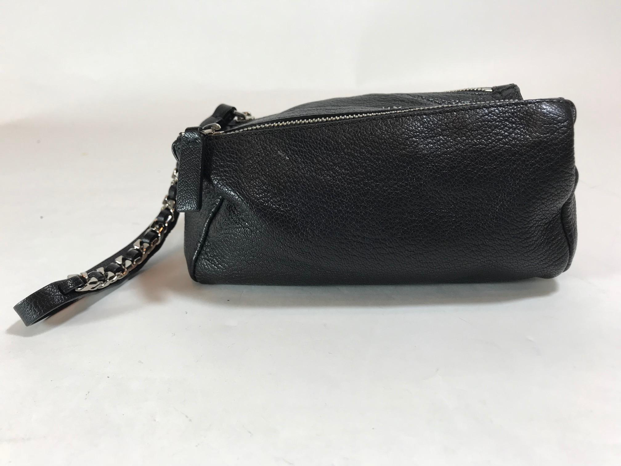 Black grained leather. Silver-tone hardware. Single flat wrist strap featuring chain-link embellishment. Main compartment featuring top zipper closure. Single exterior zip pocket. Tonal canvas lining. Estimated Retail: $670