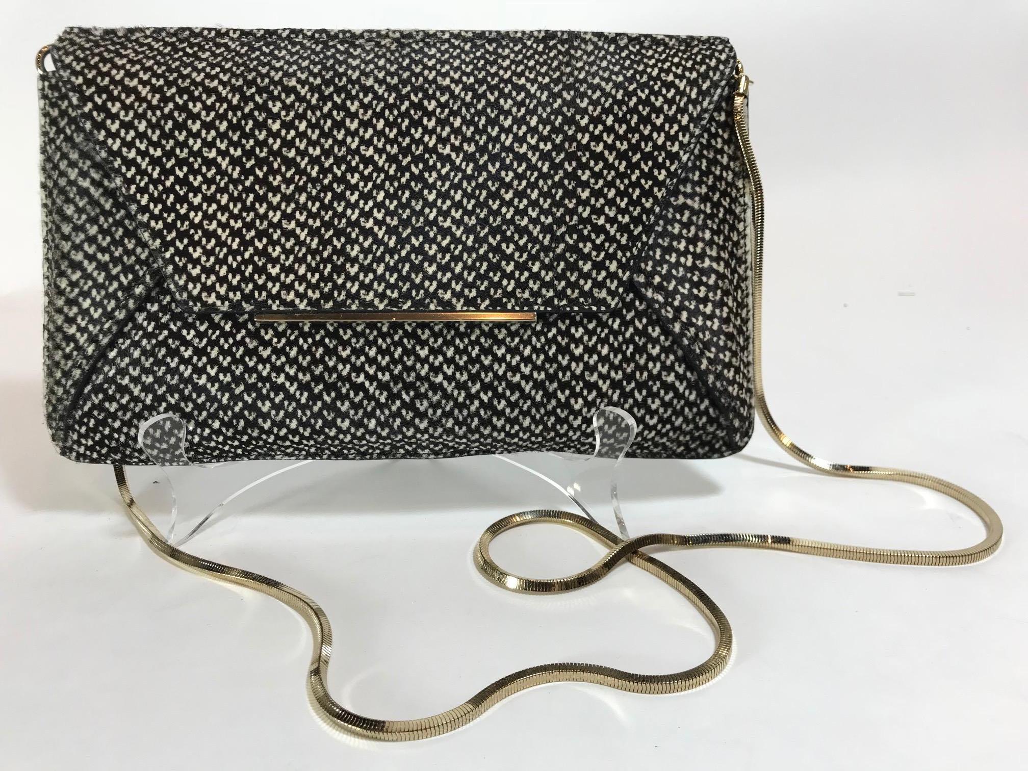 Brown and creme printed ponyhair Lanvin envelope clutch with gold-tone hardware, optional chain-link shoulder strap, bar adornment at front flap, tawny jacquard woven lining, single slip pocket at interior wall and snap closure at front flap.