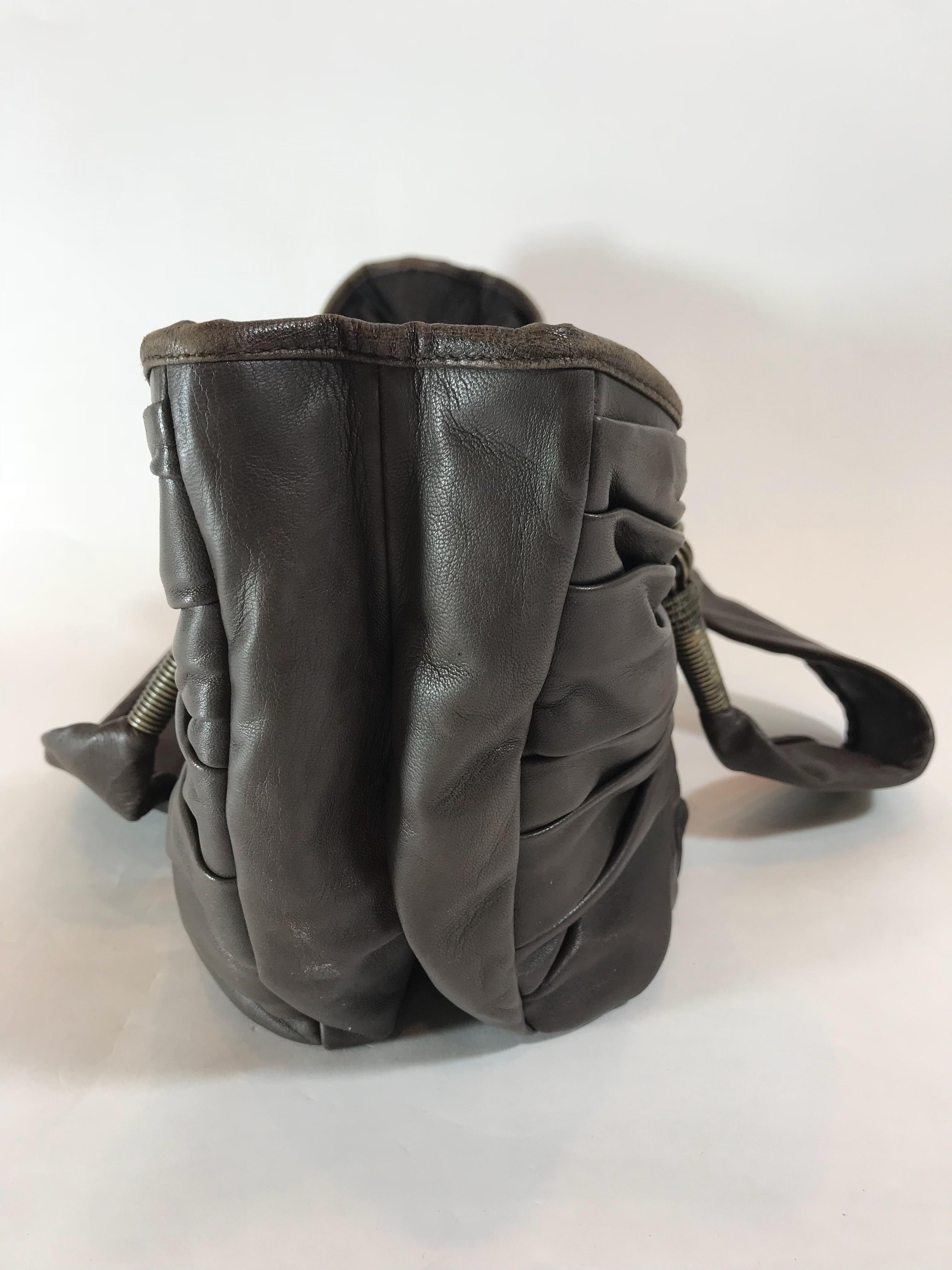 Brown pleated leather. Antiqued brass hardware. Magnetic snap closure. Dual flat shoulder straps. Tonal Diorissimo canvas lining. Dual compartments at interior, three pockets at interior wall one including a zippered closure.