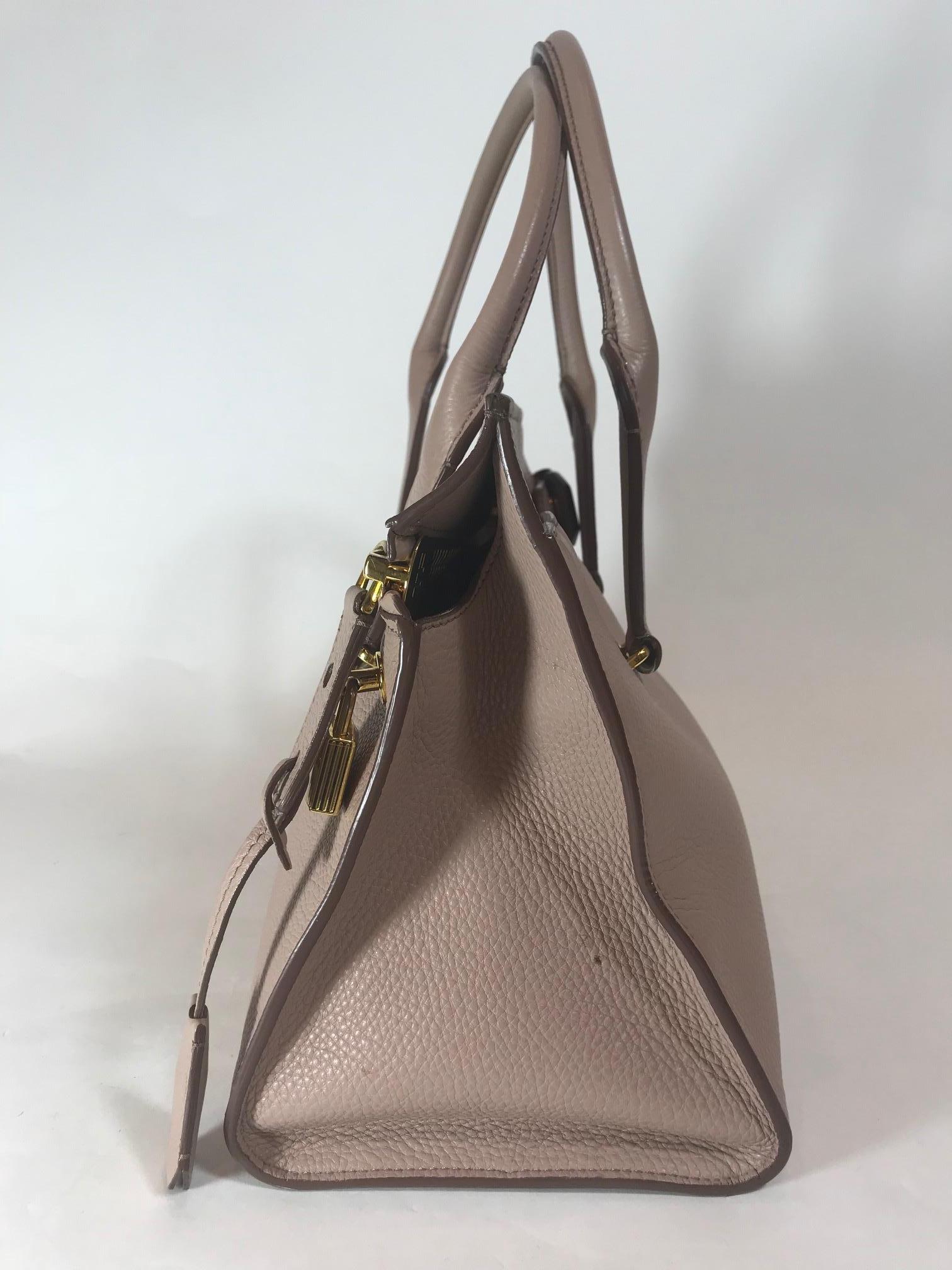 Dusty pink grained leather. Gold-tone hardware. Main zip closure at back featuring oversized zipper. Dual rolled shoulder straps. Single slit pocket at front with magnetic snap. Beige suede lining. Two interior opened pockets and one interior
