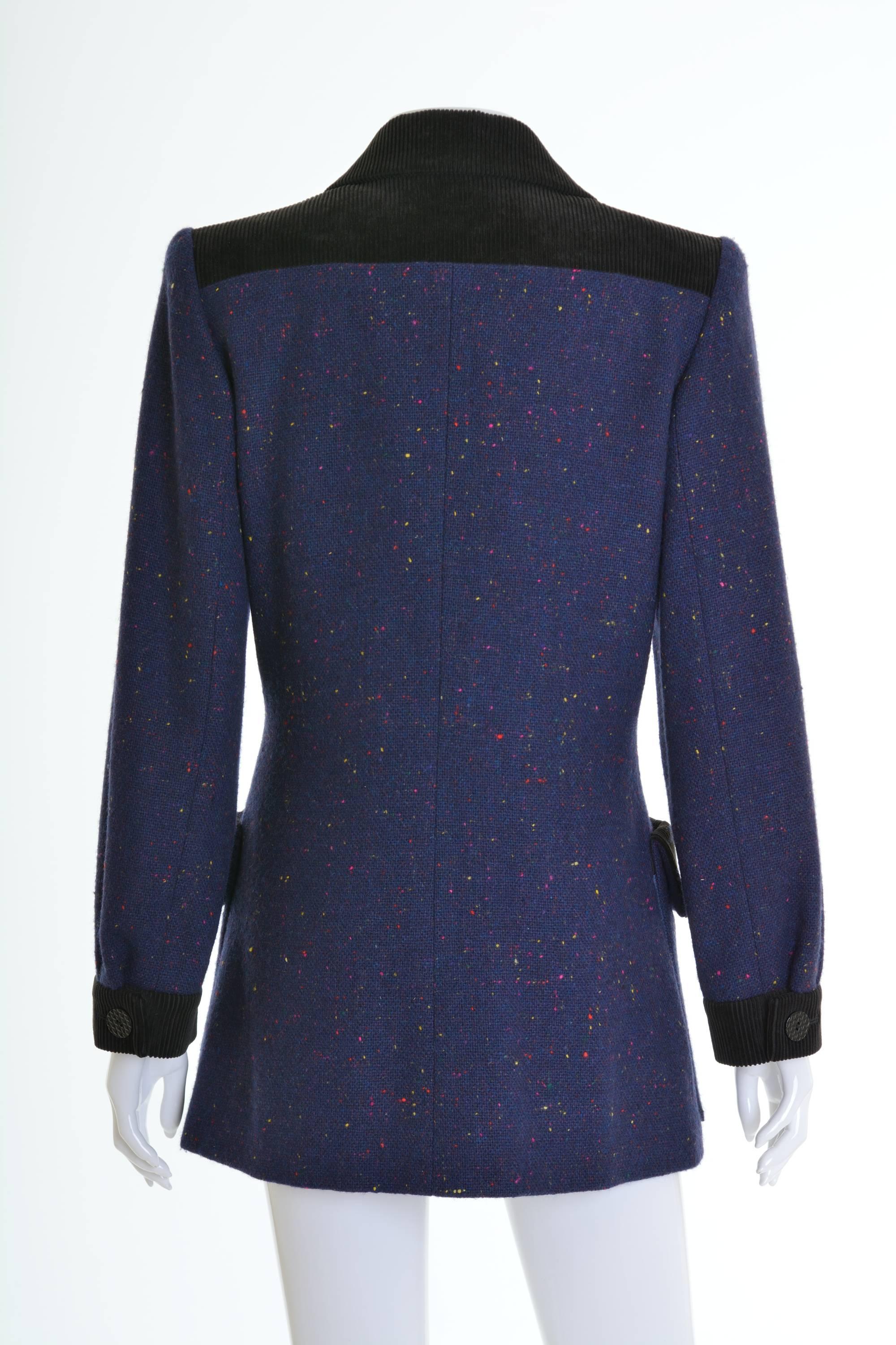 This lovely 1980s Yves Saint Laurent long jackett is in a purple blue woolen salt and pepper fabric. It has black corduroy details, two fronts pockets, long sleeves, plastic buttons closure and is fully lined. It has slightly padded shoulders with