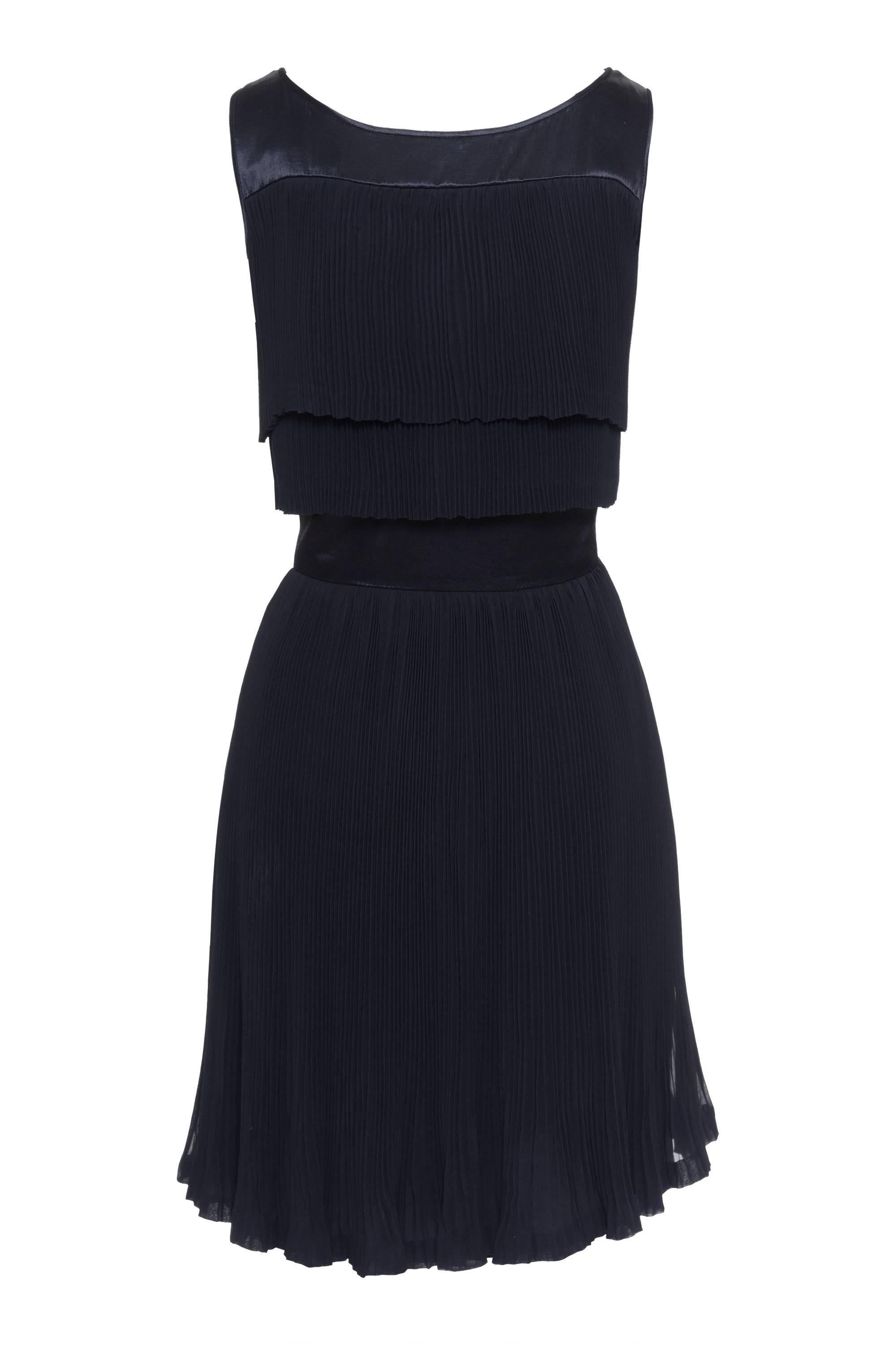 This gorgeous 1980s black 60s style cocktail dress by VALENTINO BOUTIQUE has accordion pleat layers on the top and on the skirt, made with silk and satin, round neckline, and a side zip and snap buttons on the pleats closure. Made in