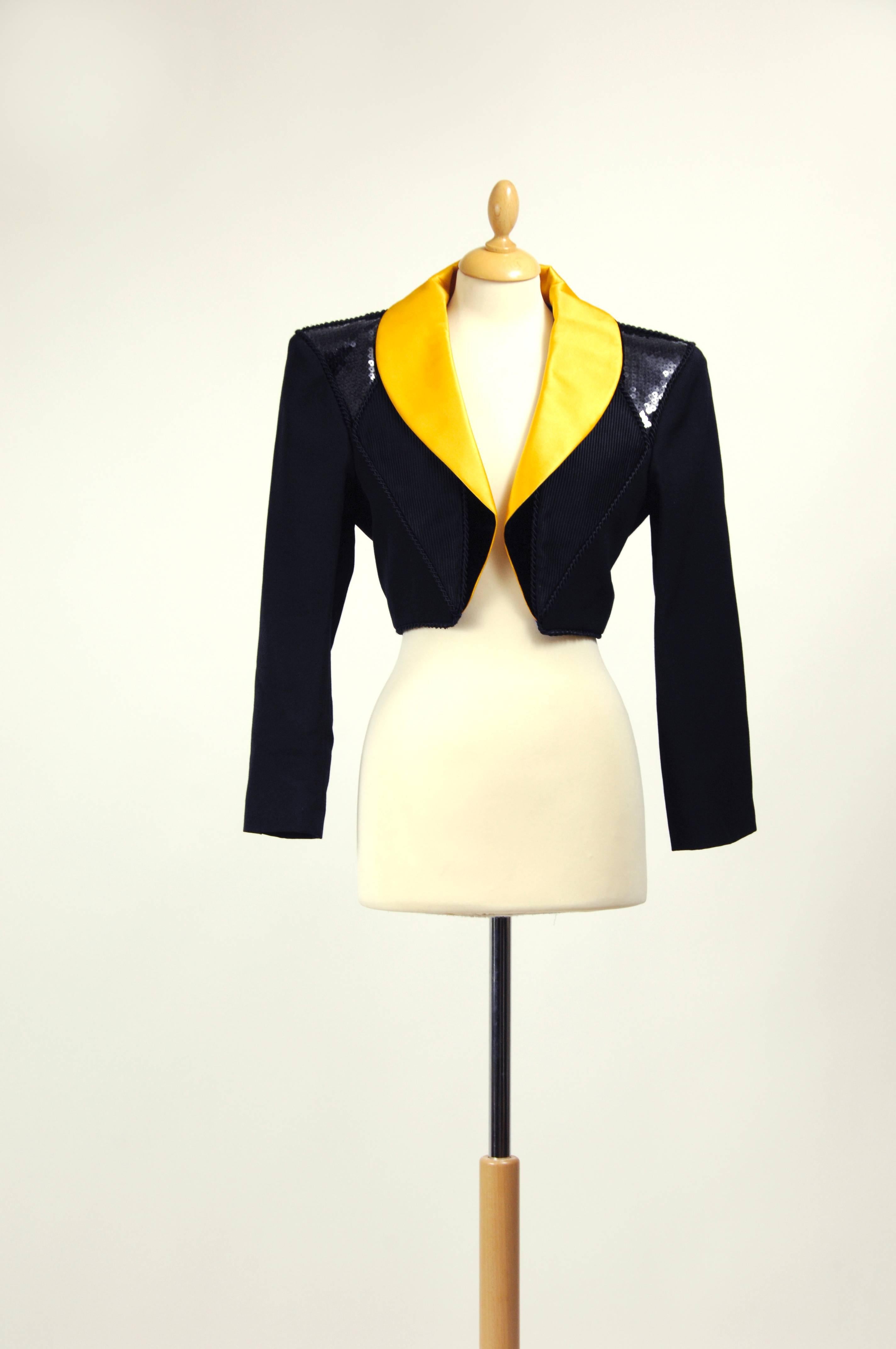 This gorgeous and iconic Yves Saint Laurent 1980s bolero jacket is in a black fabric with yellow satin collar and black sequins and velvet details. It has large padded shoulders, buttons in the cuffs and purple satin lined.

Measurement:
Label