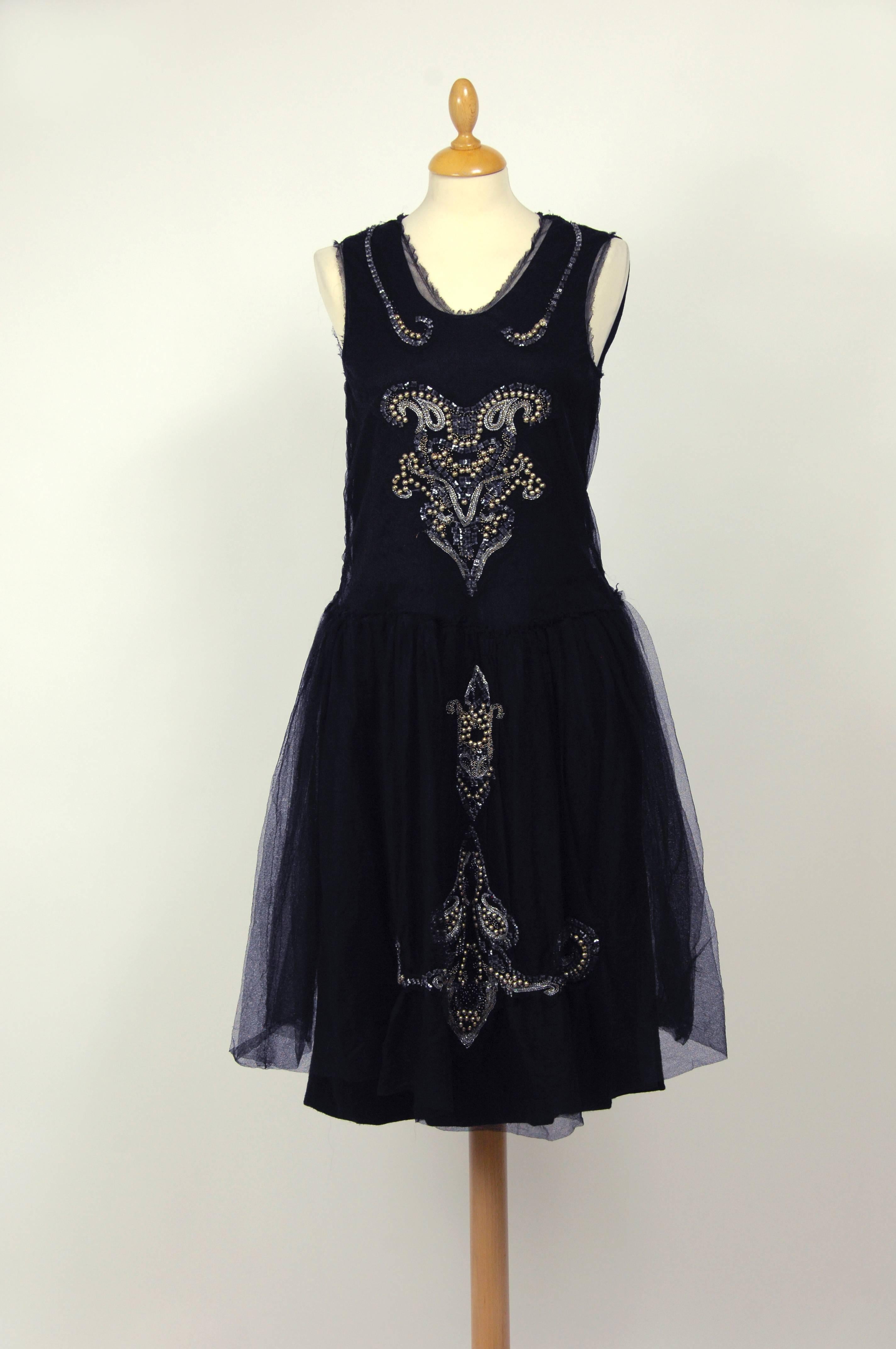 This gorgeous Lanvin dress has a dress in a black woolen fabric and a 20s style dress in a black tulle fabric. The woolen dress is sleeveless and has side zip closure and crinoline hips and skirt lined. The tulle dress is sleeveless and embroidered