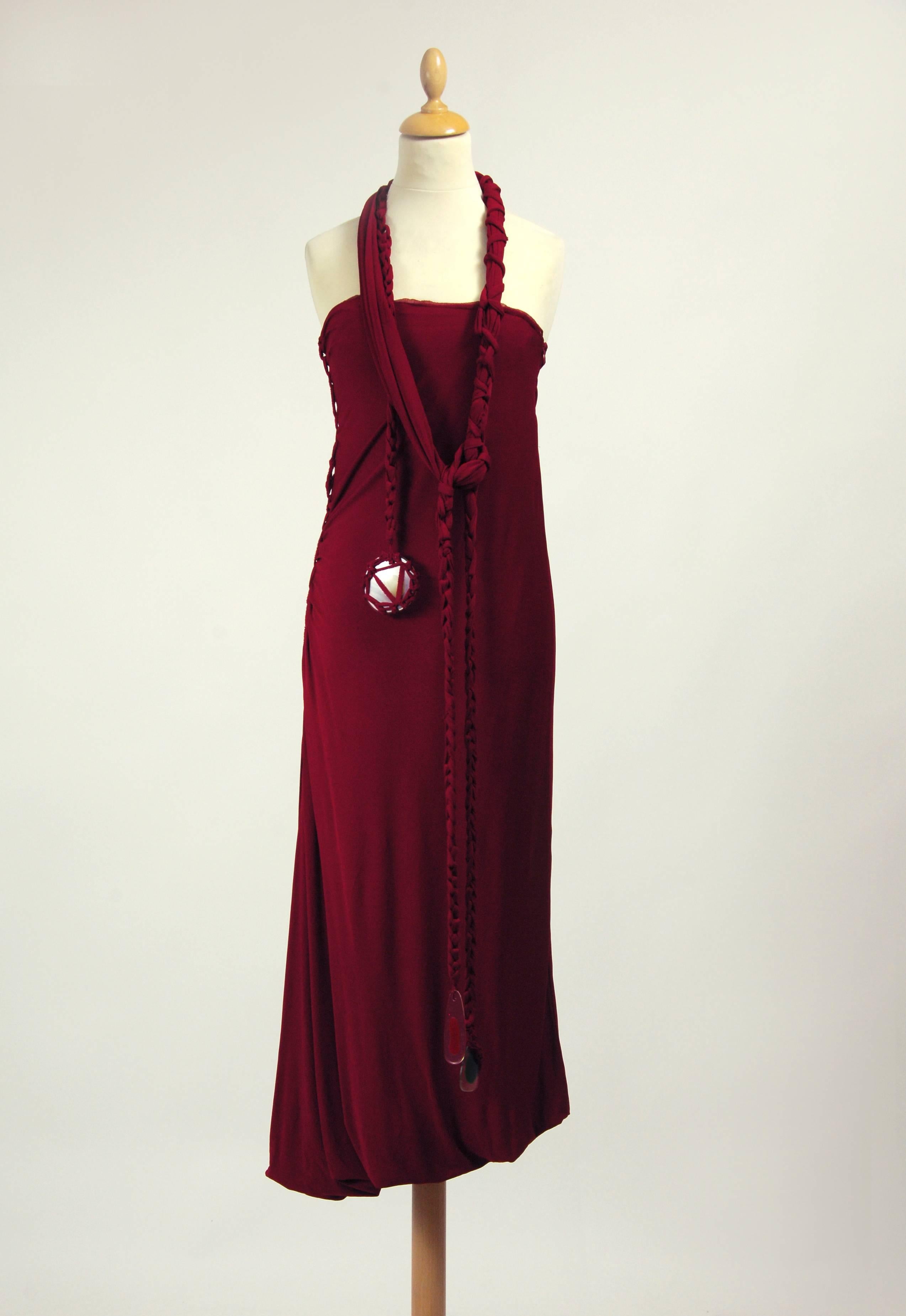 This gorgeous Jean Paul Gaultier dress in in a dark magenta red jersey silk fabric. It include an amazing shoulder straps or sash belt with plastic details and has side zip closure. It's fully crepe pleateds silk fabric