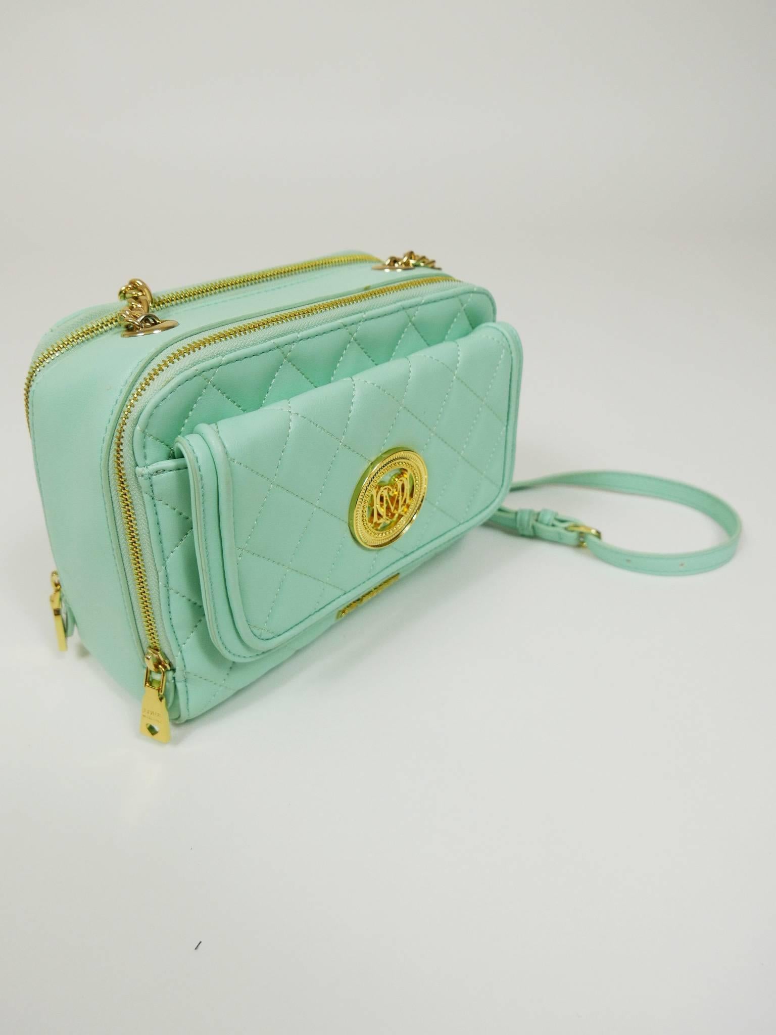 This glamourous Moschino mini bag is in a mint green quilted faux leather with golden metal Logo detail. It has removable shoulder strap chain in golden metal and mint green faux leather, zip closures with gold hardware and front pocket, inside Love