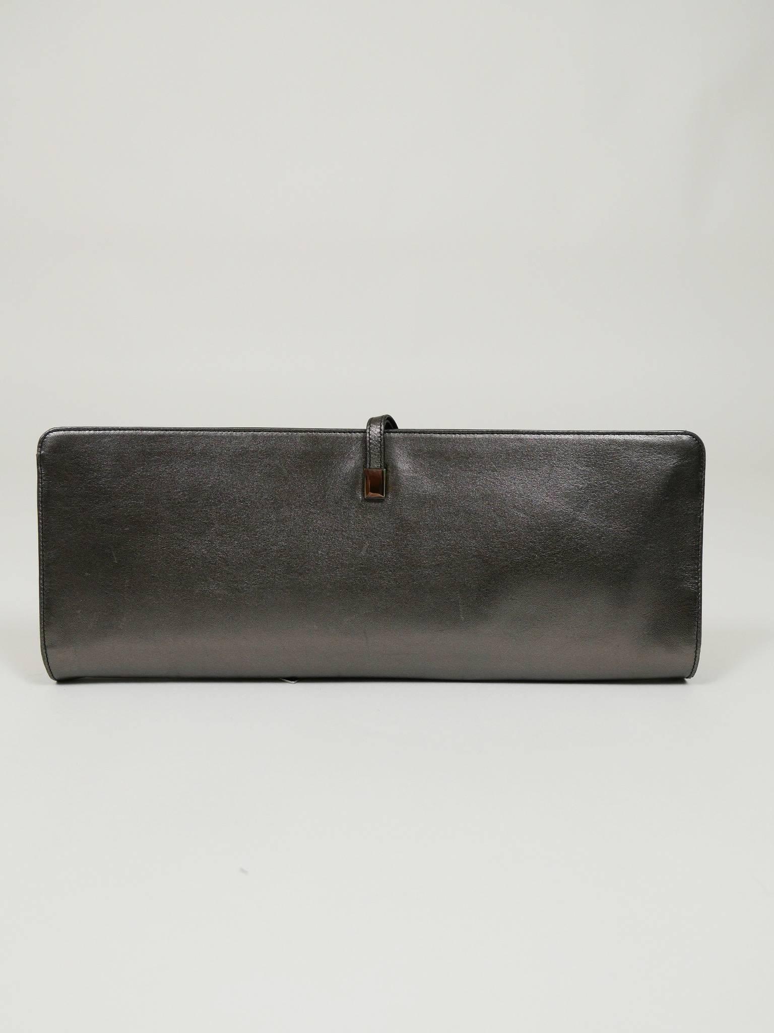 This glamourous authentic Yves Saint Laurent clutch purse is in a metallic dark gray leather. It has wrap around strap, original brand inside, multiple pockets and automatic button closure and signed satin fabric lined. It's perfect for any