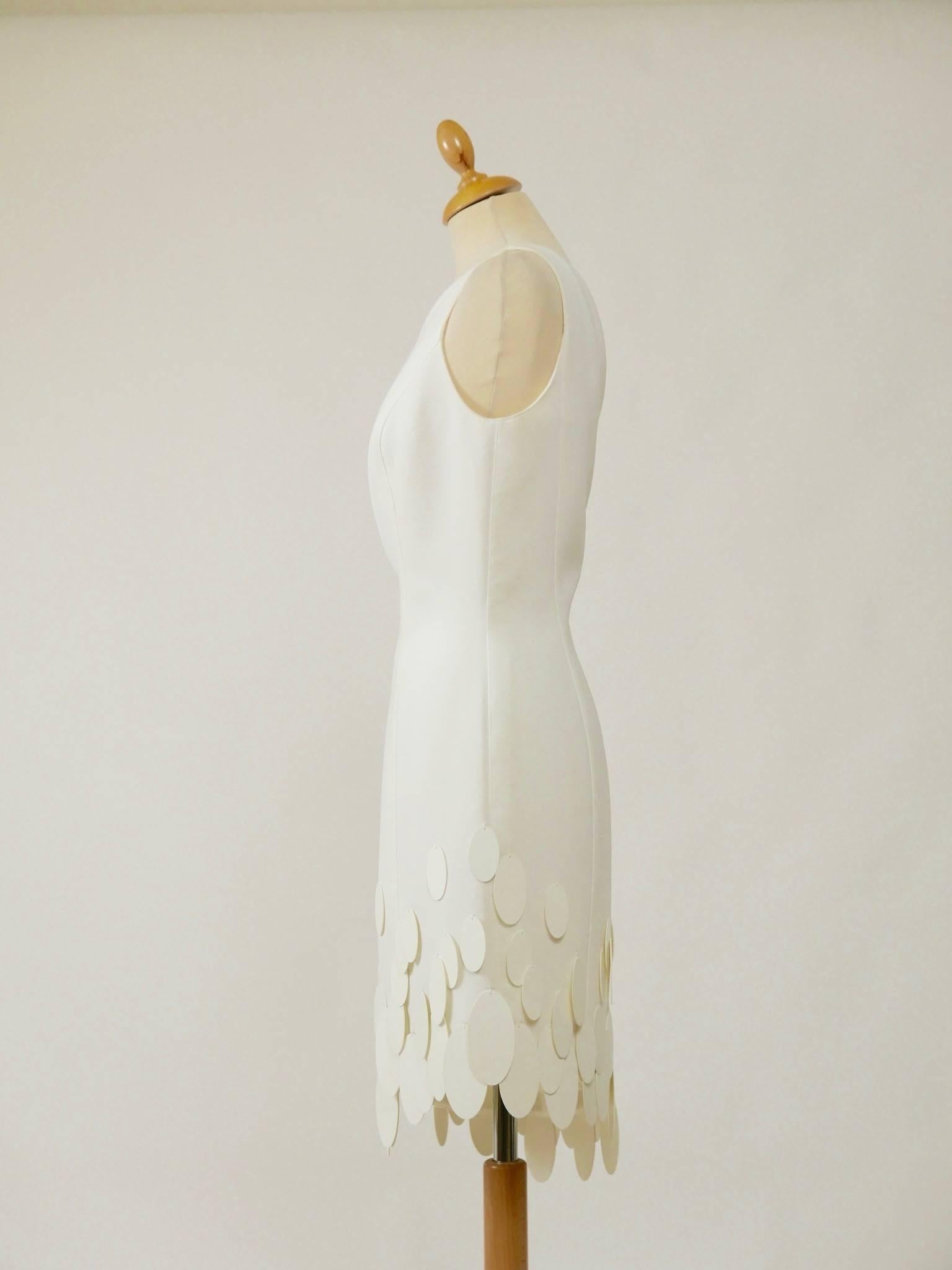 This amazing and feminine dress of Thierry Mugler from the late 1980s has a Space Age style. It's in white fabric. It has one shoulder and is cut in a curved classic Mugler style. It has plastic pendant details, back side zip closure and is fully